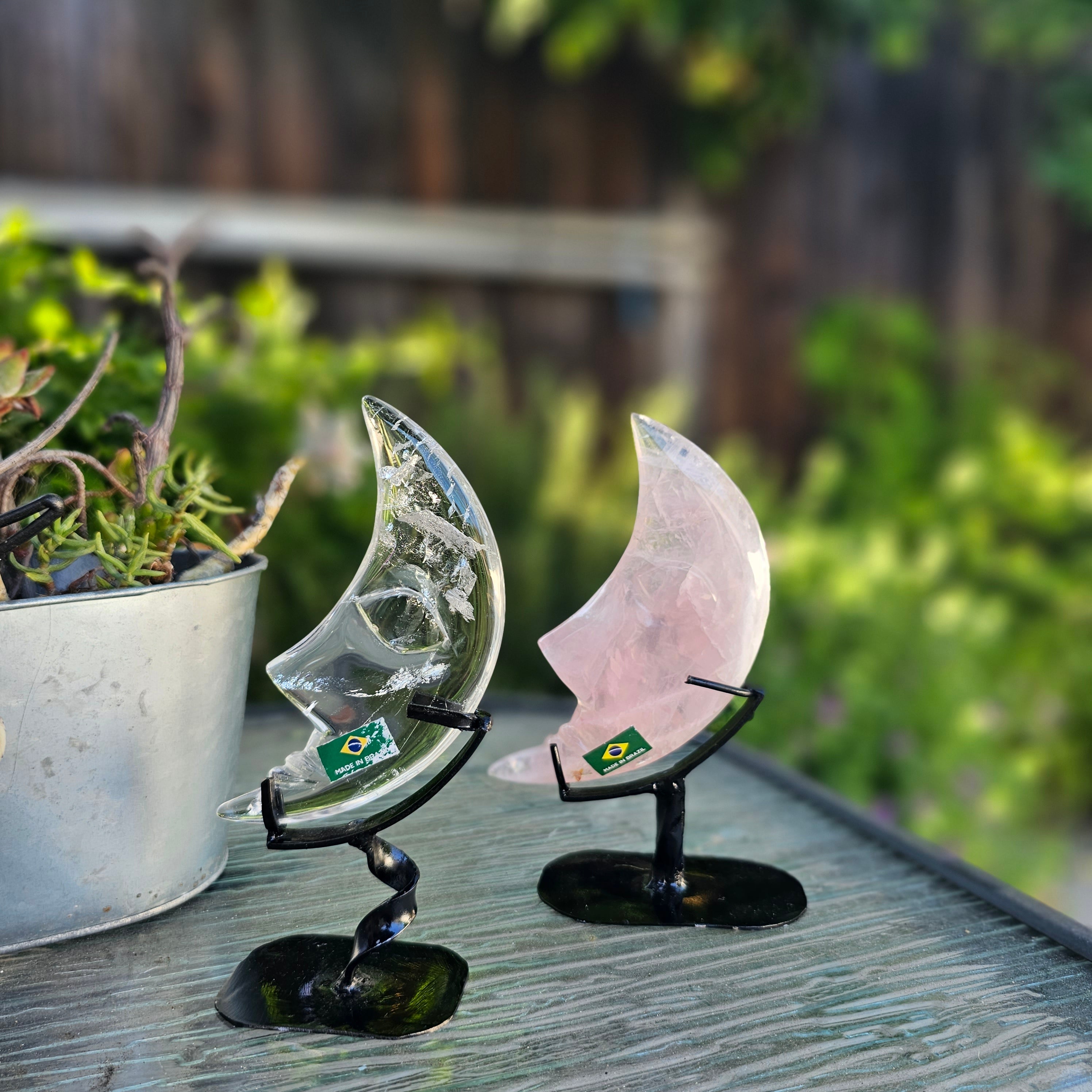 A beautifully hand-carved crescent moon made of quartz and rose quartz, mounted on a stylish twisted metal base, showcasing intricate details.