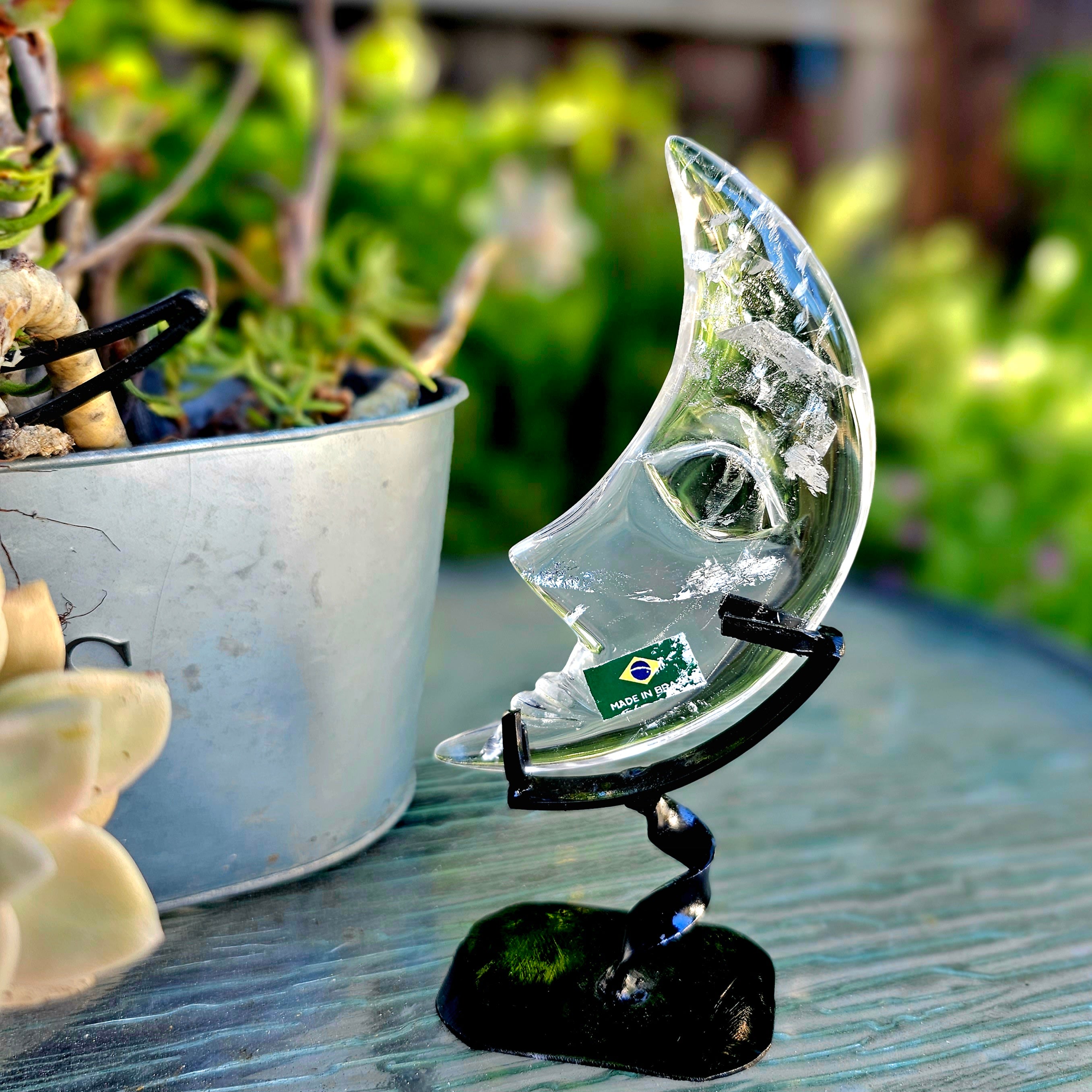 A beautifully hand-carved crescent moon made of quartz and rose quartz, mounted on a stylish twisted metal base, showcasing intricate details.