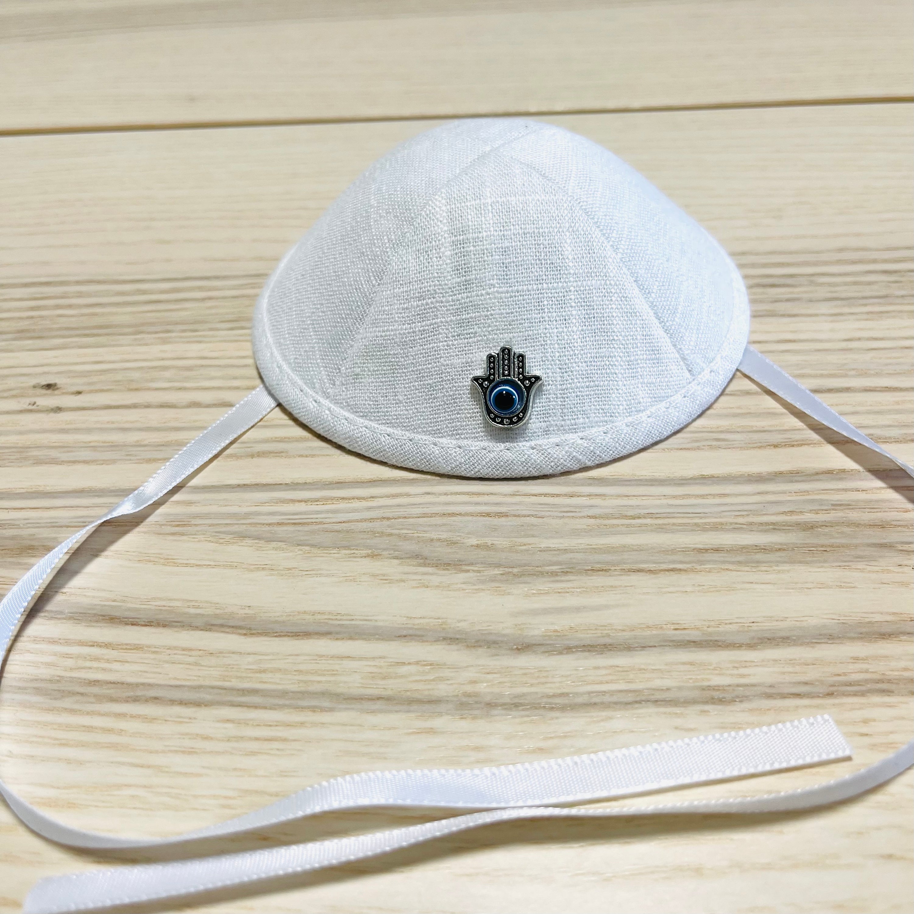 Father and baby boy wearing matching Hamsa linen kippahs for Brit Milah, showcasing elegant design and teddy bear embroidery.
