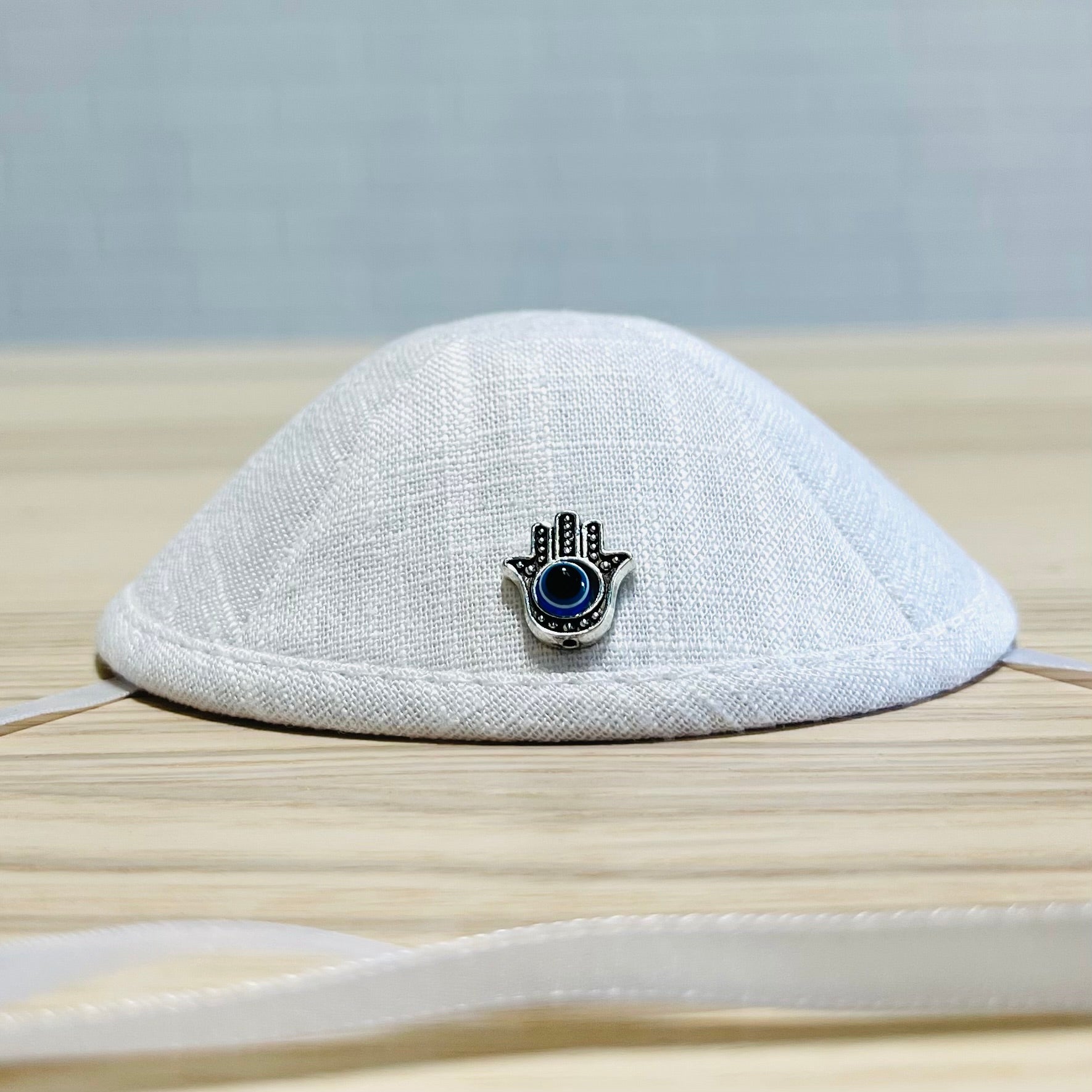 Father and baby boy wearing matching Hamsa linen kippahs for Brit Milah, showcasing elegant design and teddy bear embroidery.