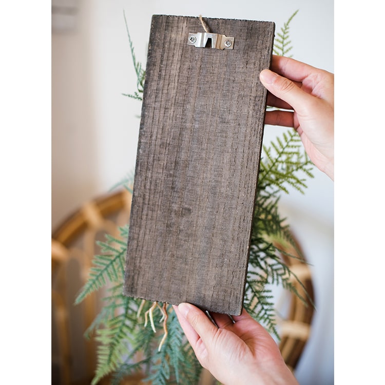 Faux Artificial Asparagus Setaceus hanging decoration on a wooden board, showcasing realistic green fronds.