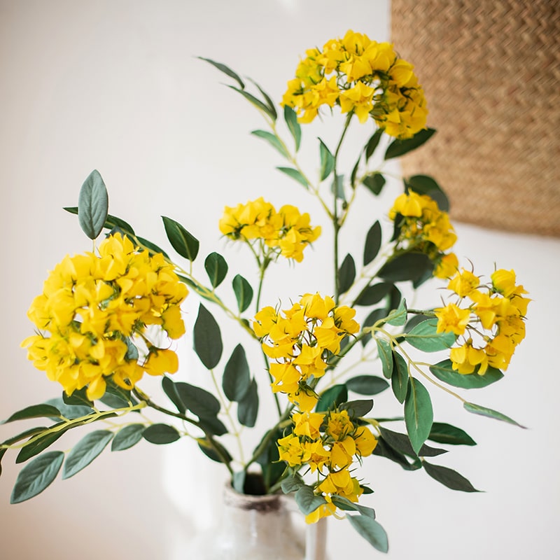 A 27-inch tall Faux Silk Artificial Senna Plant Flower Stem in pink, white, and yellow colors, showcasing realistic silk petals and lush greenery.