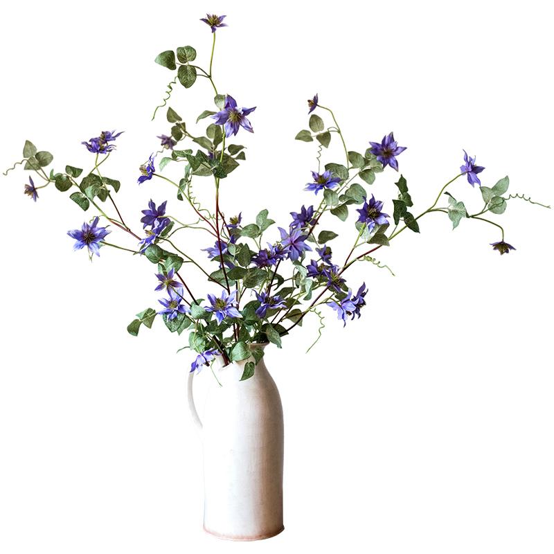 A 40-inch tall faux silk clematis flower stem in purple, featuring seven realistic blooms and lush green foliage, perfect for home decor.