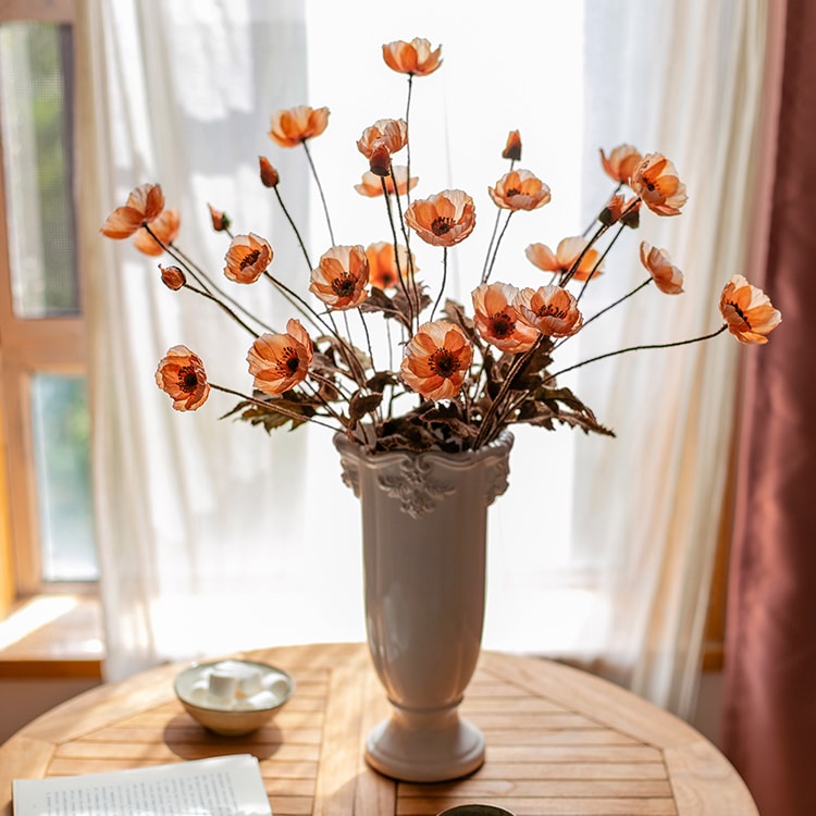 A vibrant orange faux silk poppy flower stem, 23 inches tall, featuring three blooms and one bud, with green leaves.