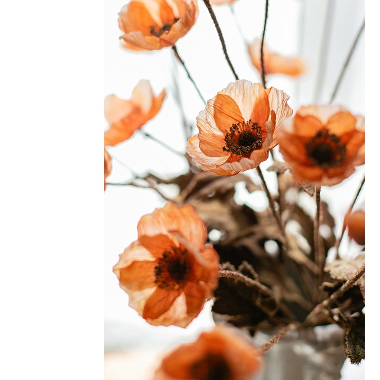 A vibrant orange faux silk poppy flower stem, 23 inches tall, featuring three blooms and one bud, with green leaves.