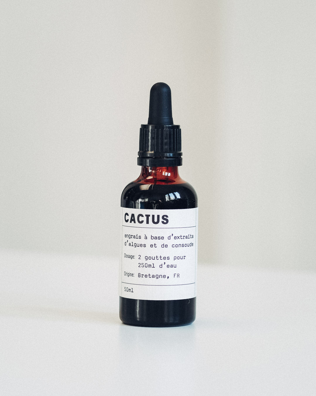 Botella de fertilizante natural para cactus y suculentas, con etiqueta informativa y fondo verde.