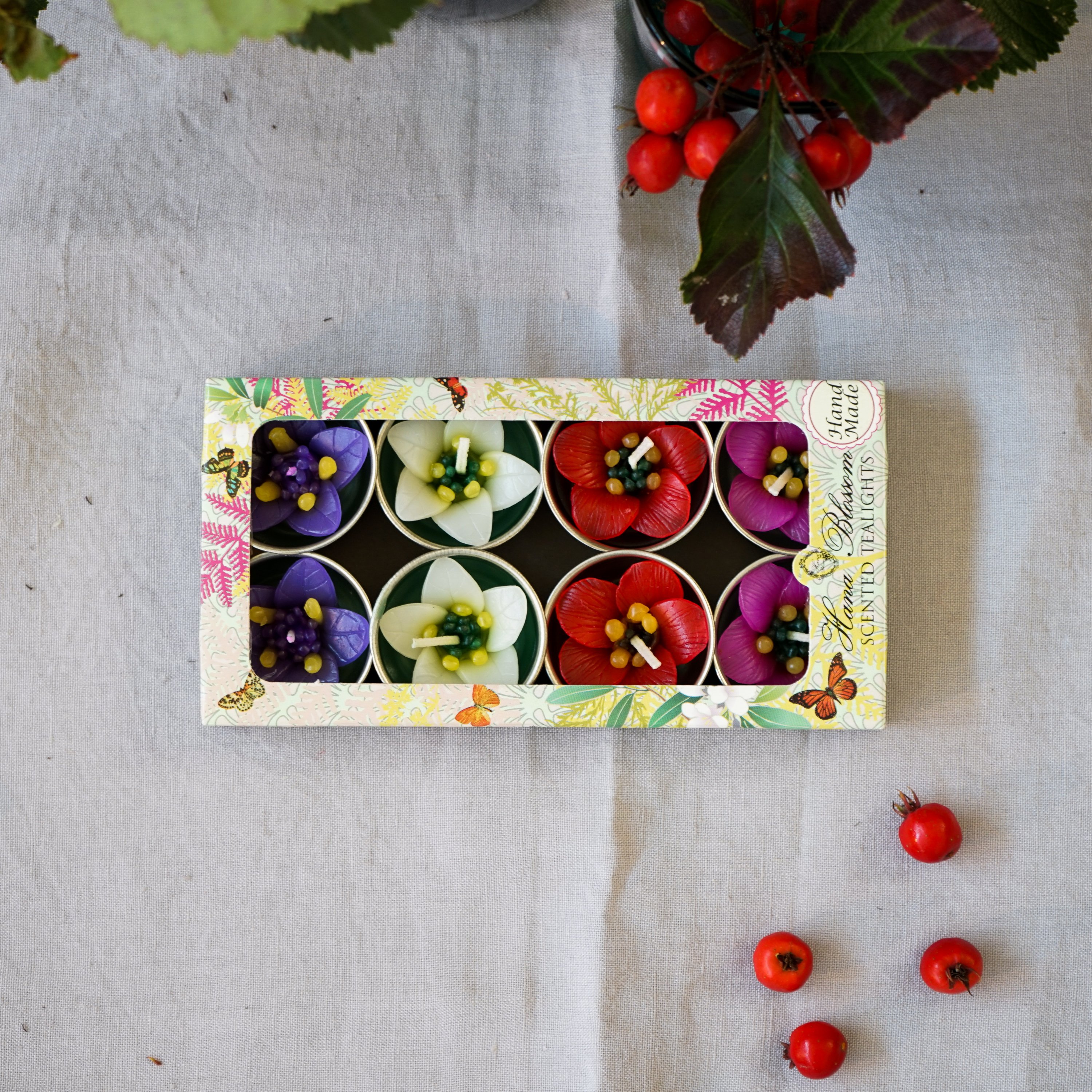 Four Garden Flower Scented Tealights in vibrant colors, showcasing floral designs with a soft glow.