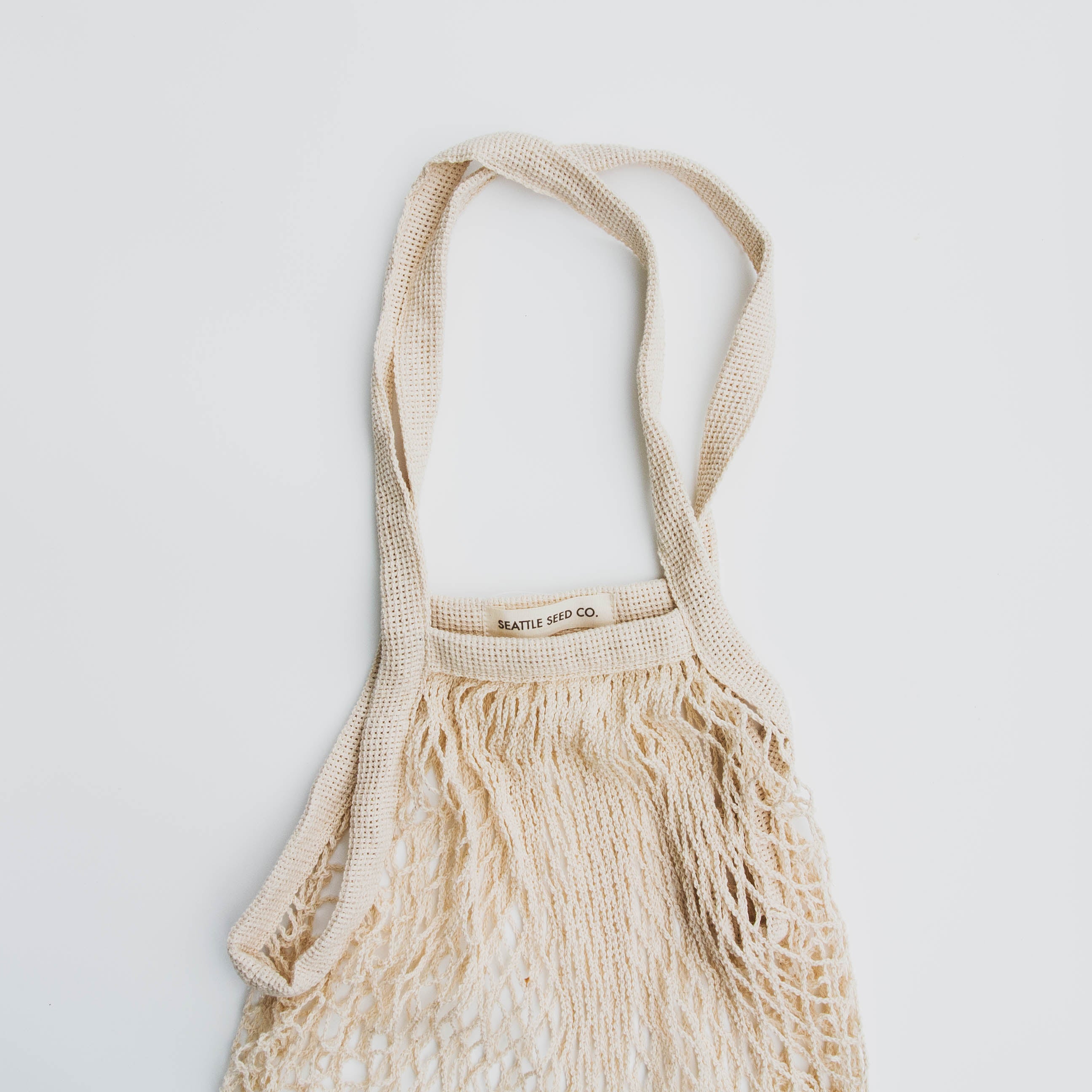 A stylish French Market Tote made of durable cotton string, showcasing its expandable design and natural color, perfect for shopping and travel.