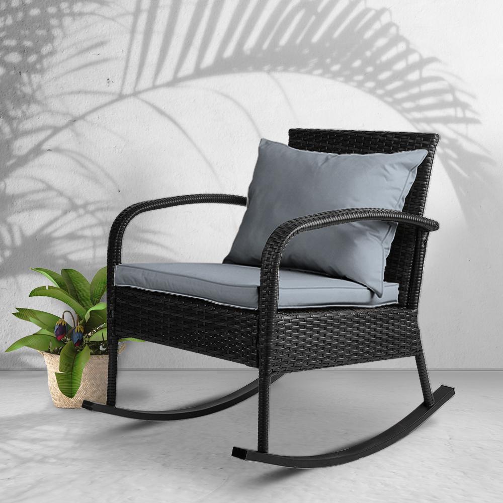Gardeon Outdoor Rocking Chair in black wicker with grey cushions, set in a garden patio environment, showcasing its elegant design and comfort.