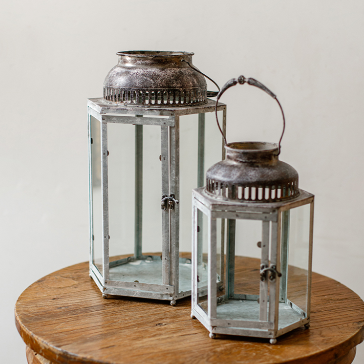 A stylish Glass Metal Lantern Candle Holder featuring a combination of glass and metal in white, gray, and rust colors, perfect for holding candles.