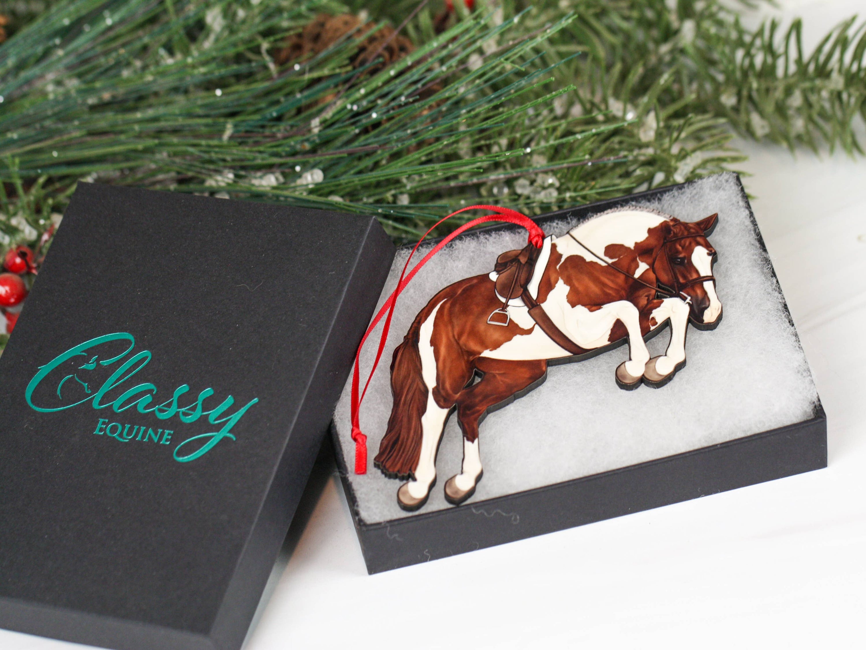 Handcrafted chestnut tobiano hunter jumper horse ornament with red and black ribbons, made from composite wood, perfect for Christmas decoration.
