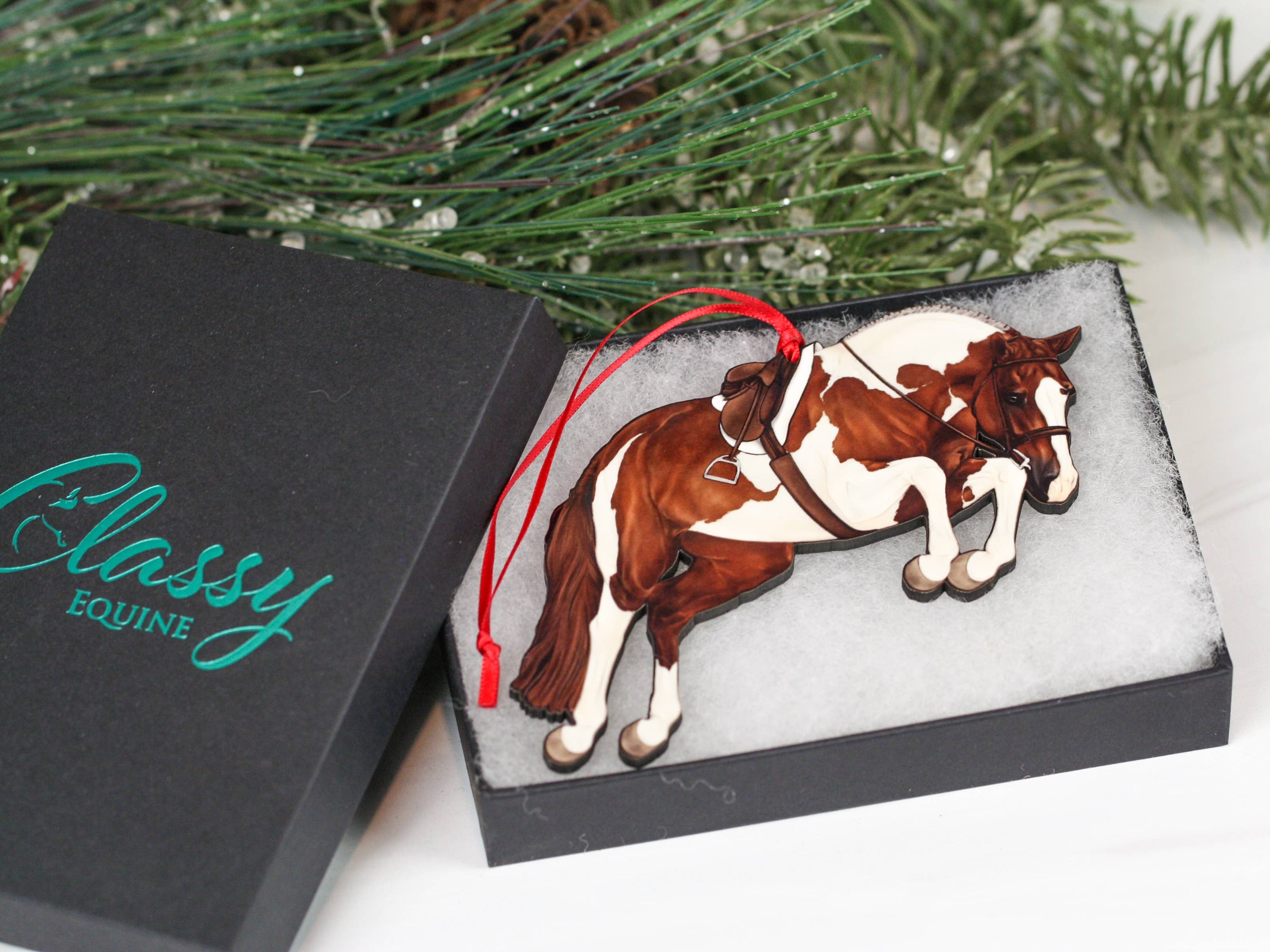 Handcrafted chestnut tobiano hunter jumper horse ornament with red and black ribbons, made from composite wood, perfect for Christmas decoration.