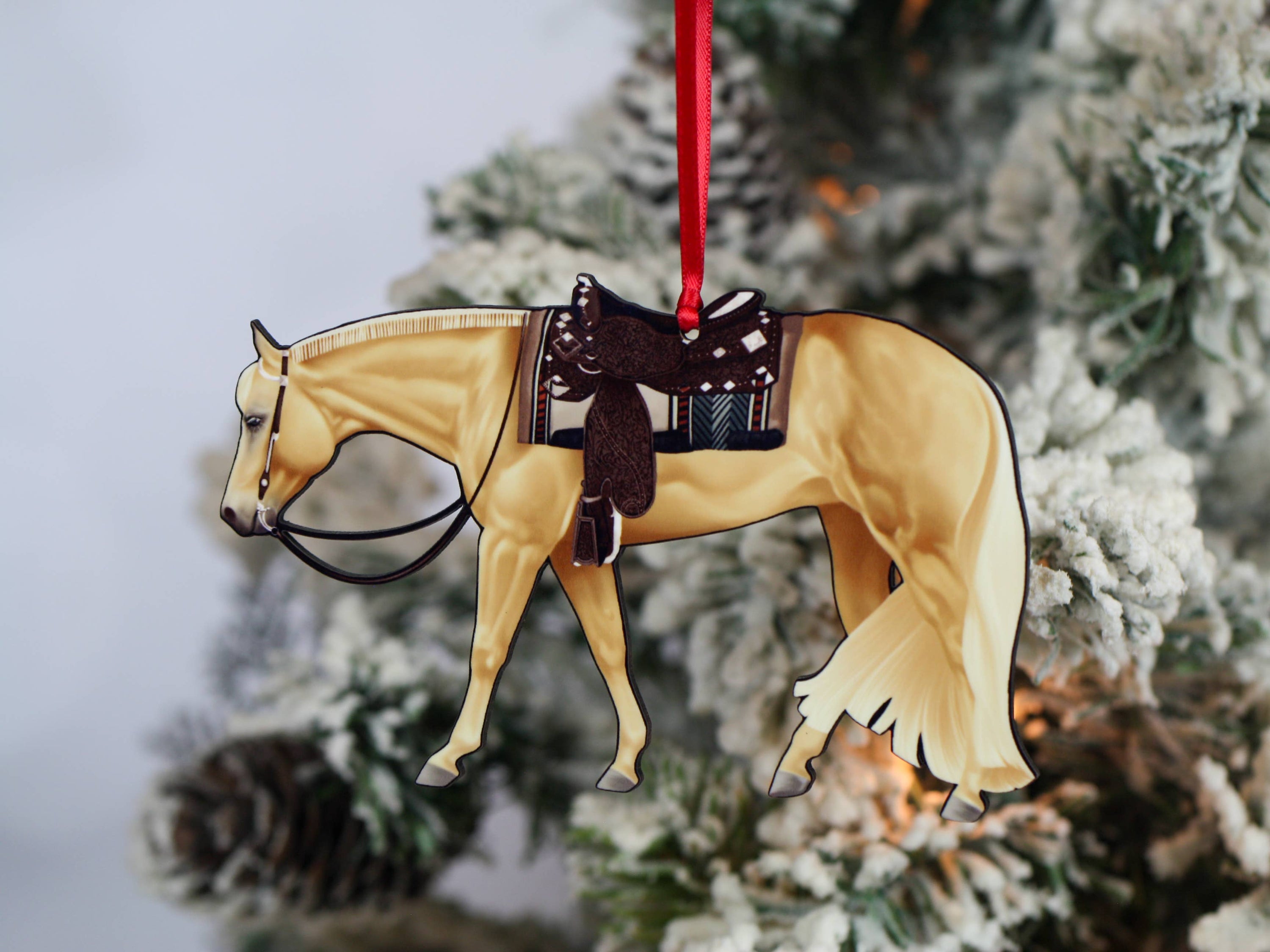 Handcrafted Palomino Quarter Horse ornament with red and black ribbons, showcasing intricate laser-cut details and glossy finish.
