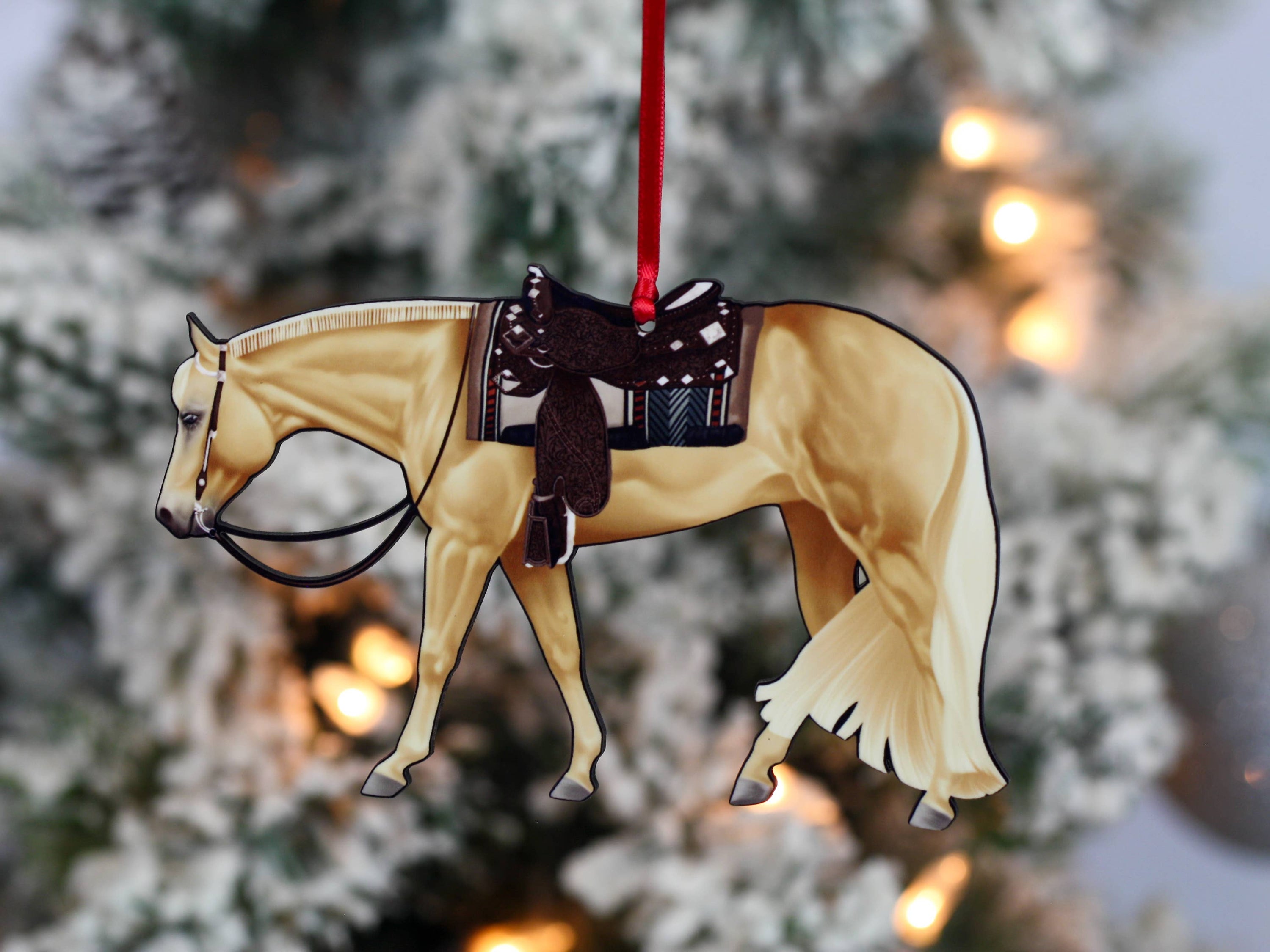 Handcrafted Palomino Quarter Horse ornament with red and black ribbons, showcasing intricate laser-cut details and glossy finish.