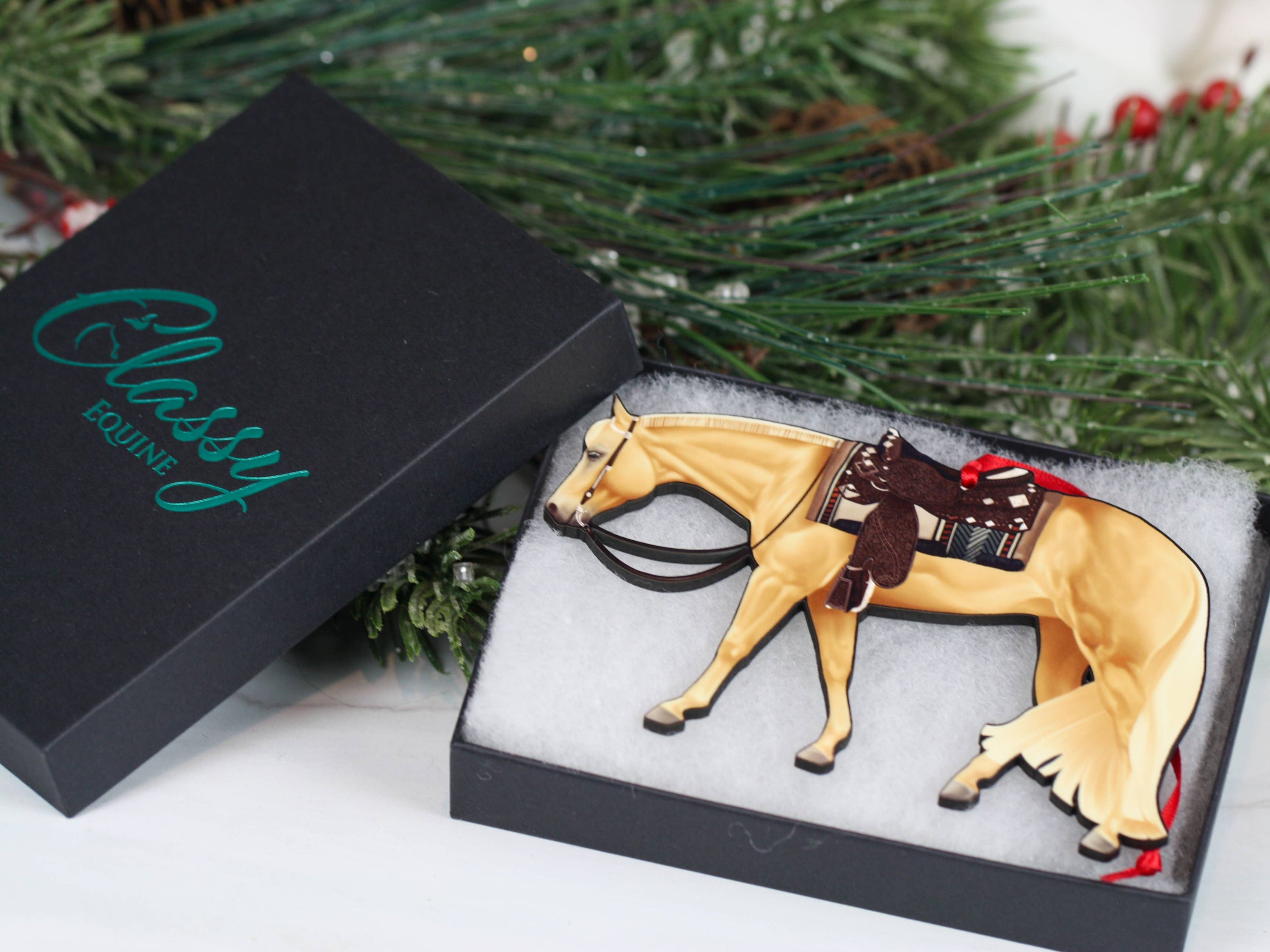 Handcrafted Palomino Quarter Horse ornament with red and black ribbons, showcasing intricate laser-cut details and glossy finish.