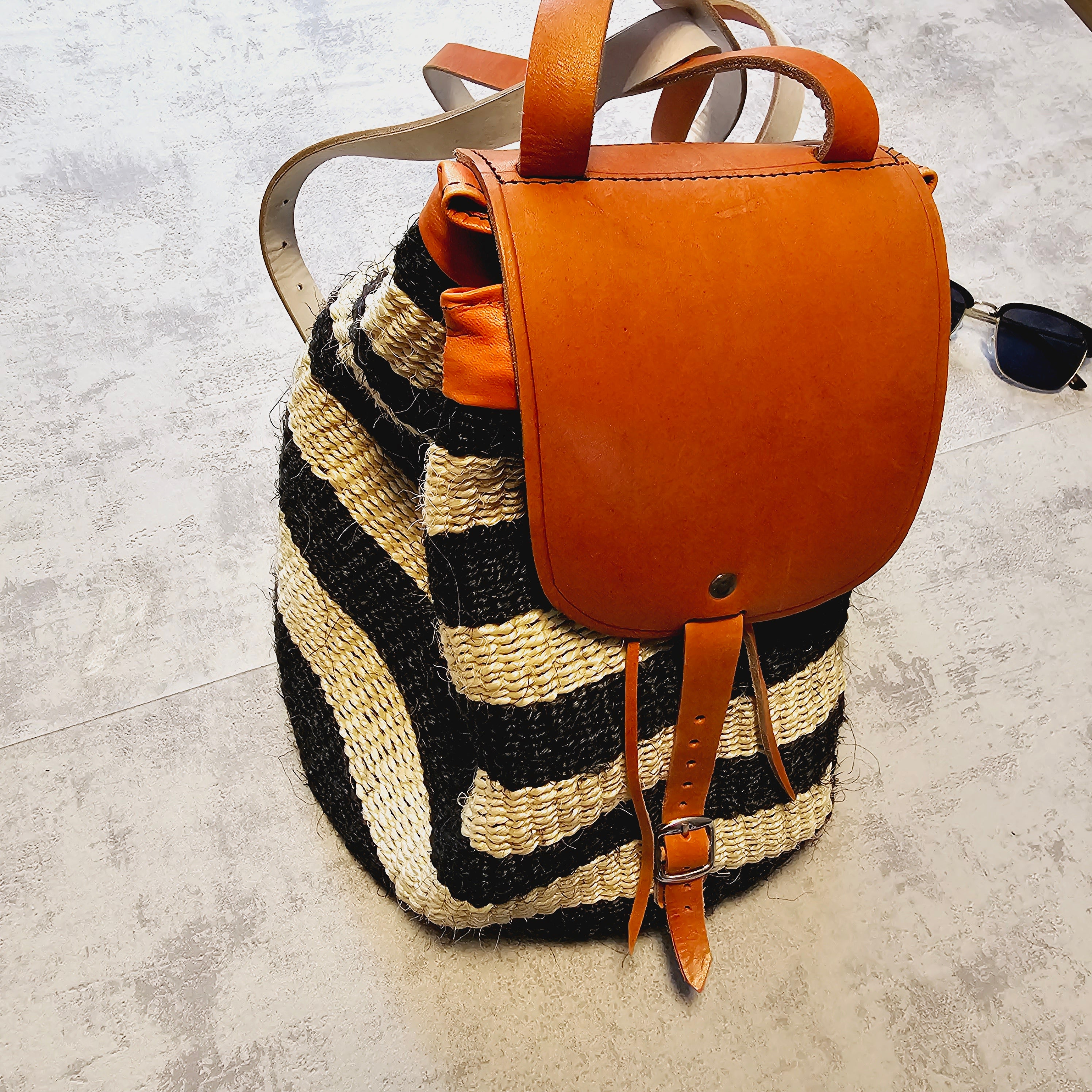 Handwoven Sisal Backpack featuring intricate patterns and leather trimmings, showcasing African craftsmanship.