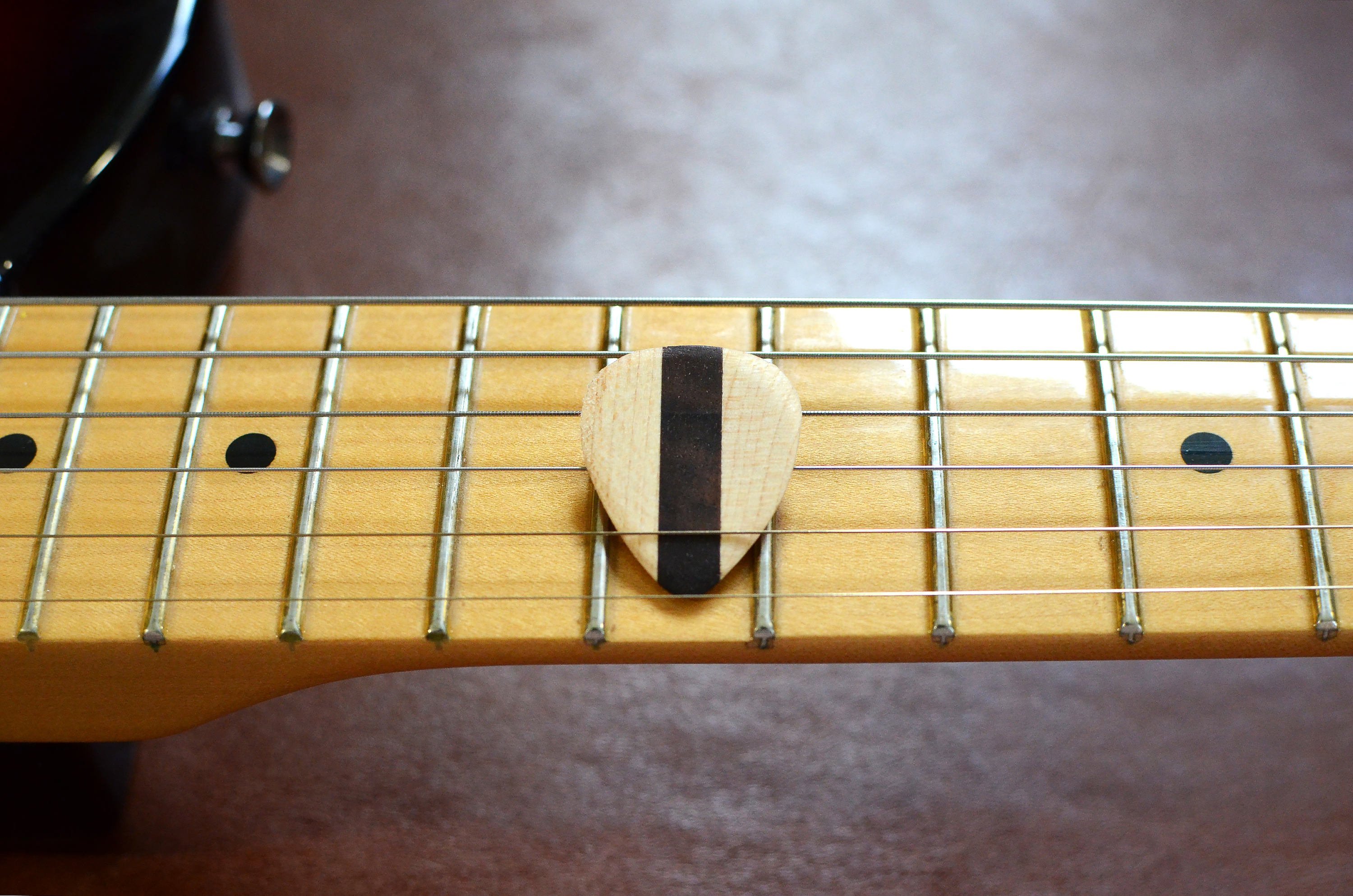 Set of 4 handcrafted hardwood guitar picks made from Black Walnut and Maple, showcasing their natural finish and unique grain patterns.