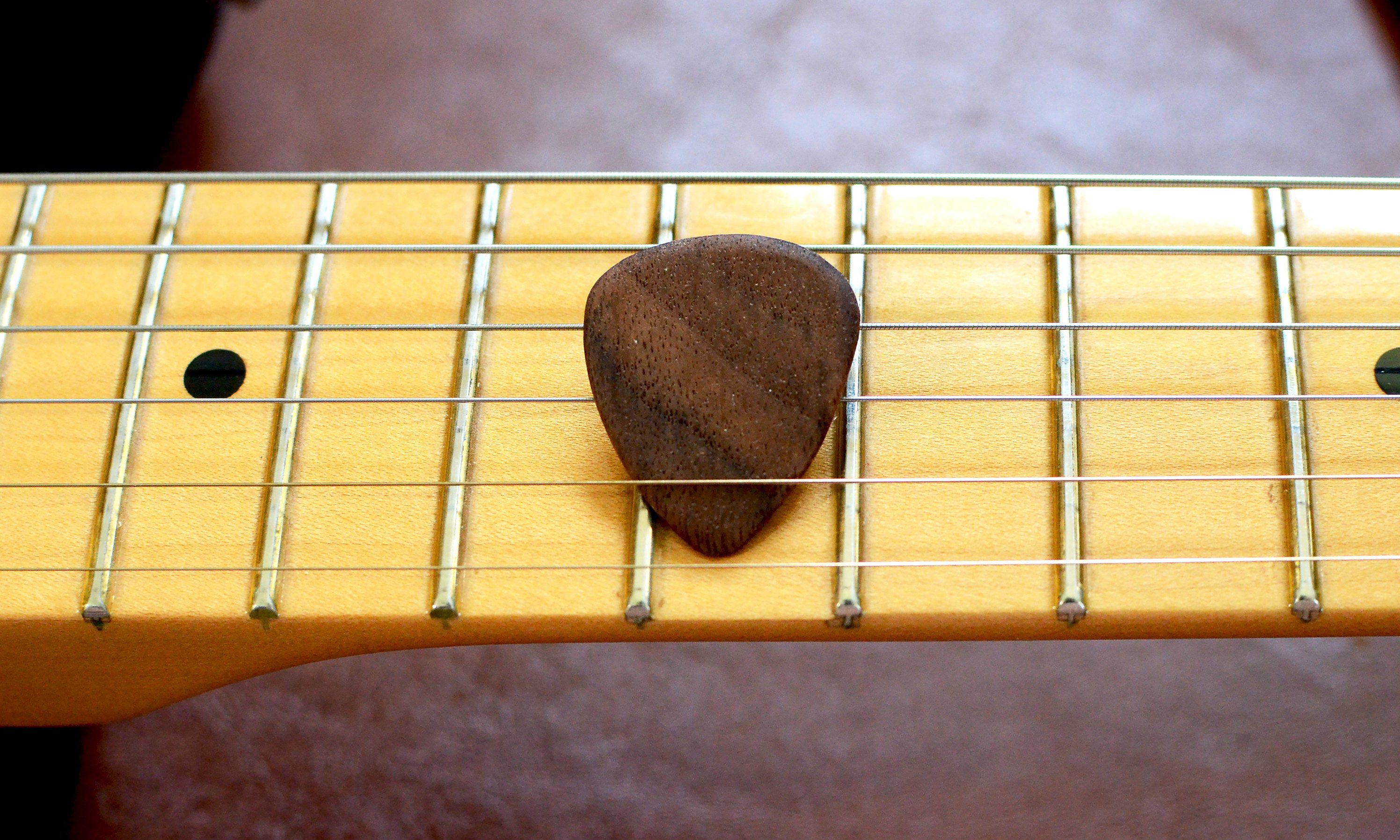 Set of 4 handcrafted hardwood guitar picks made from Black Walnut and Maple, showcasing their natural finish and unique grain patterns.