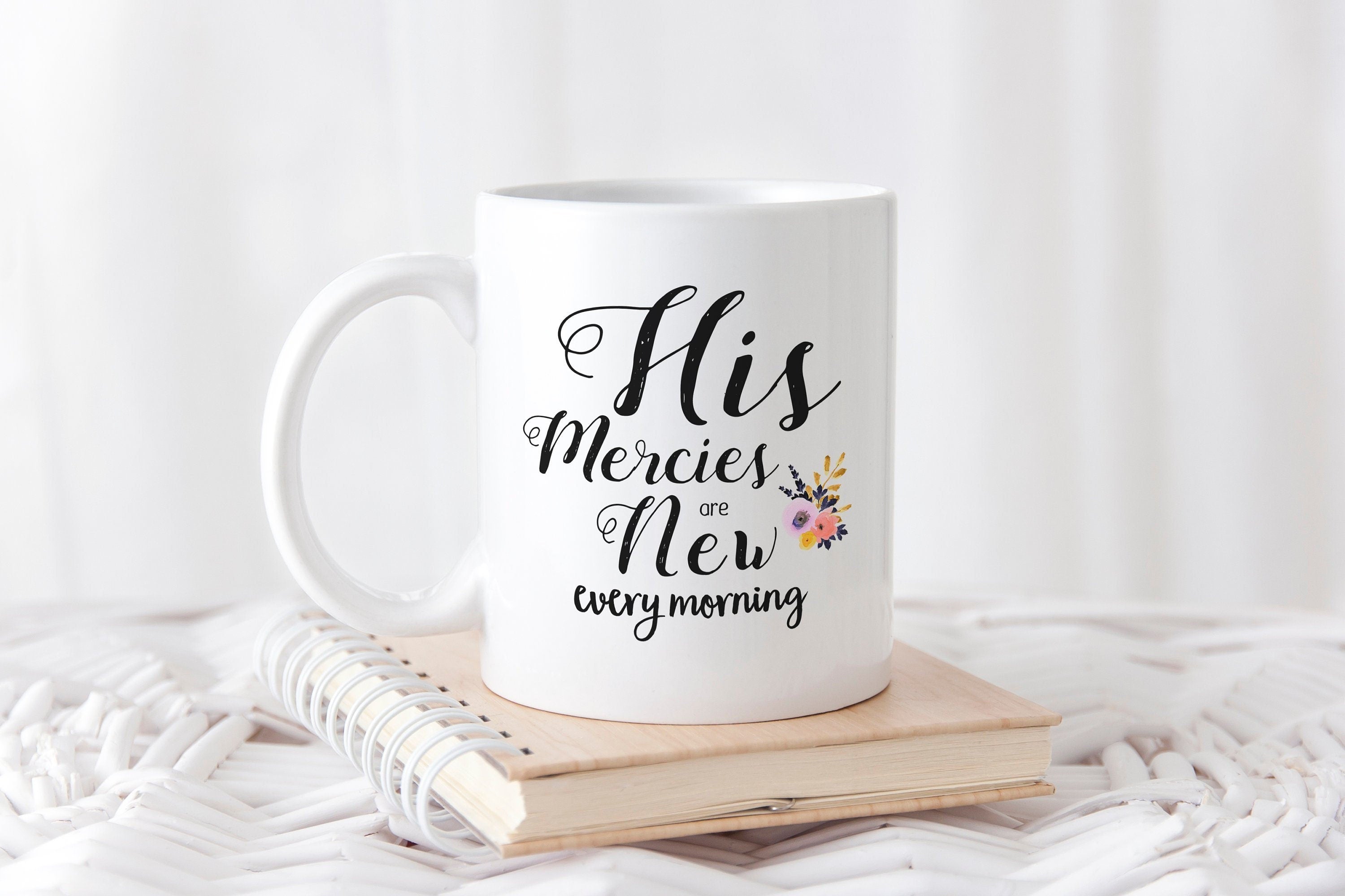 White coffee mug with hand-lettered scripture 'His Mercies are New Every Morning' printed on both sides, showcasing a warm and inspirational design.