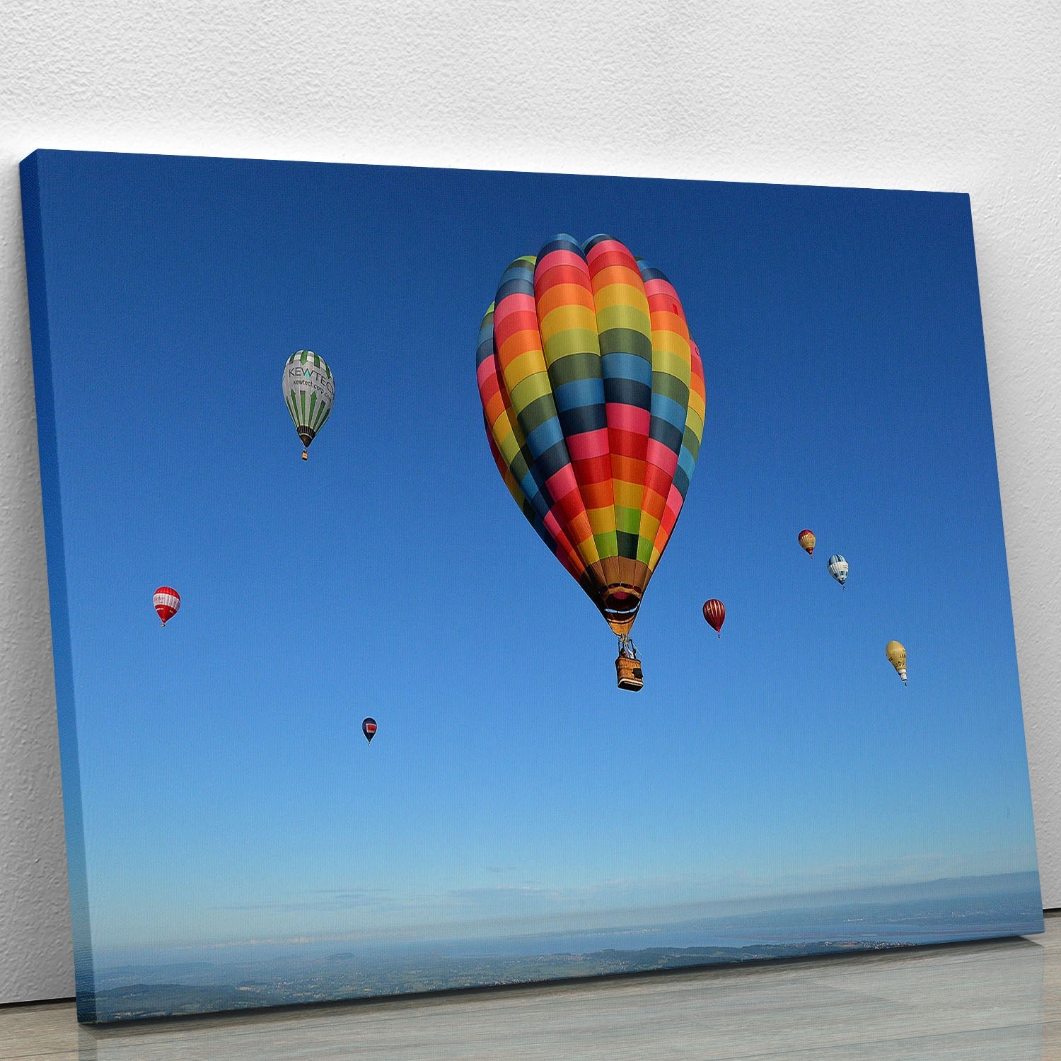 A vibrant canvas print of colorful hot air balloons soaring in a clear blue sky, adding charm and elegance to any space.