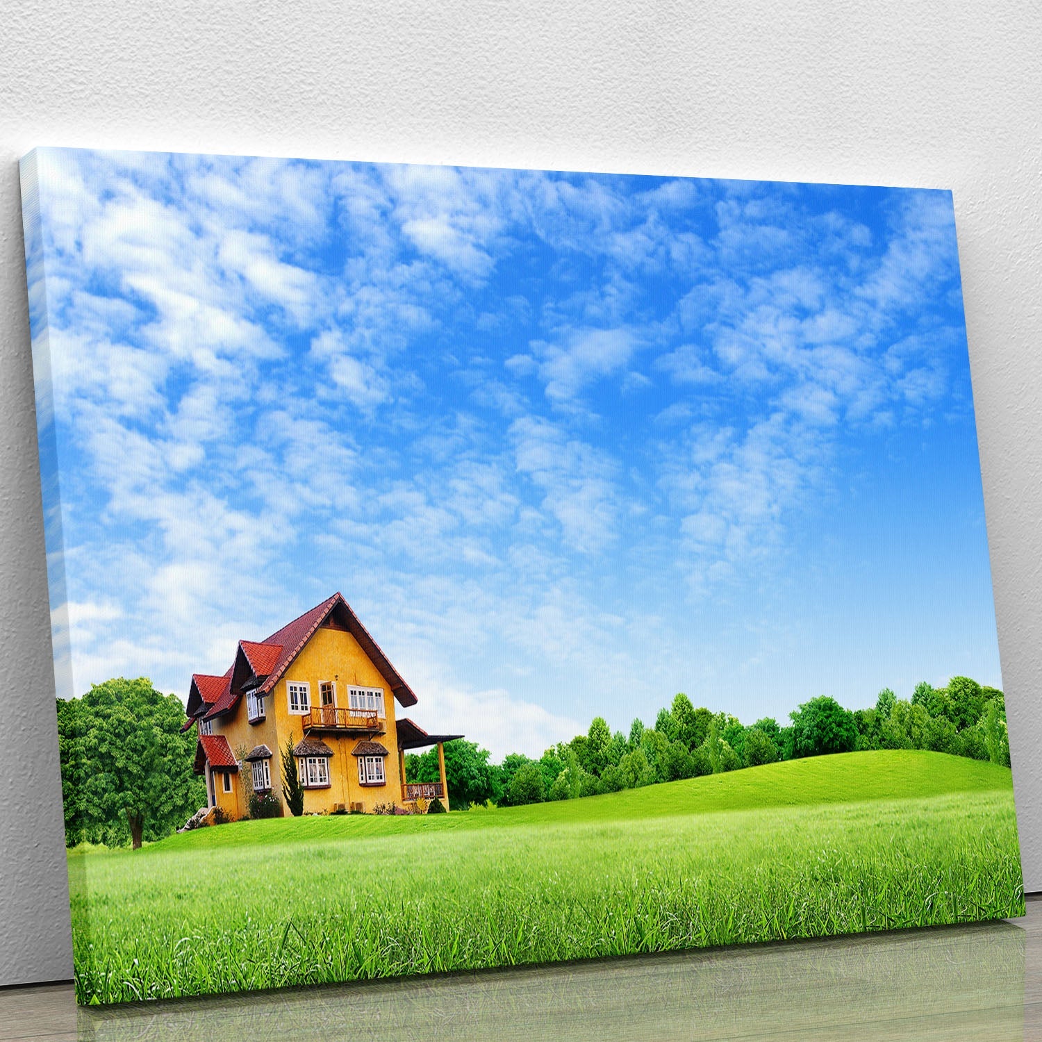 A beautiful canvas print of a house surrounded by a lush green field, showcasing vibrant colors and serene nature.