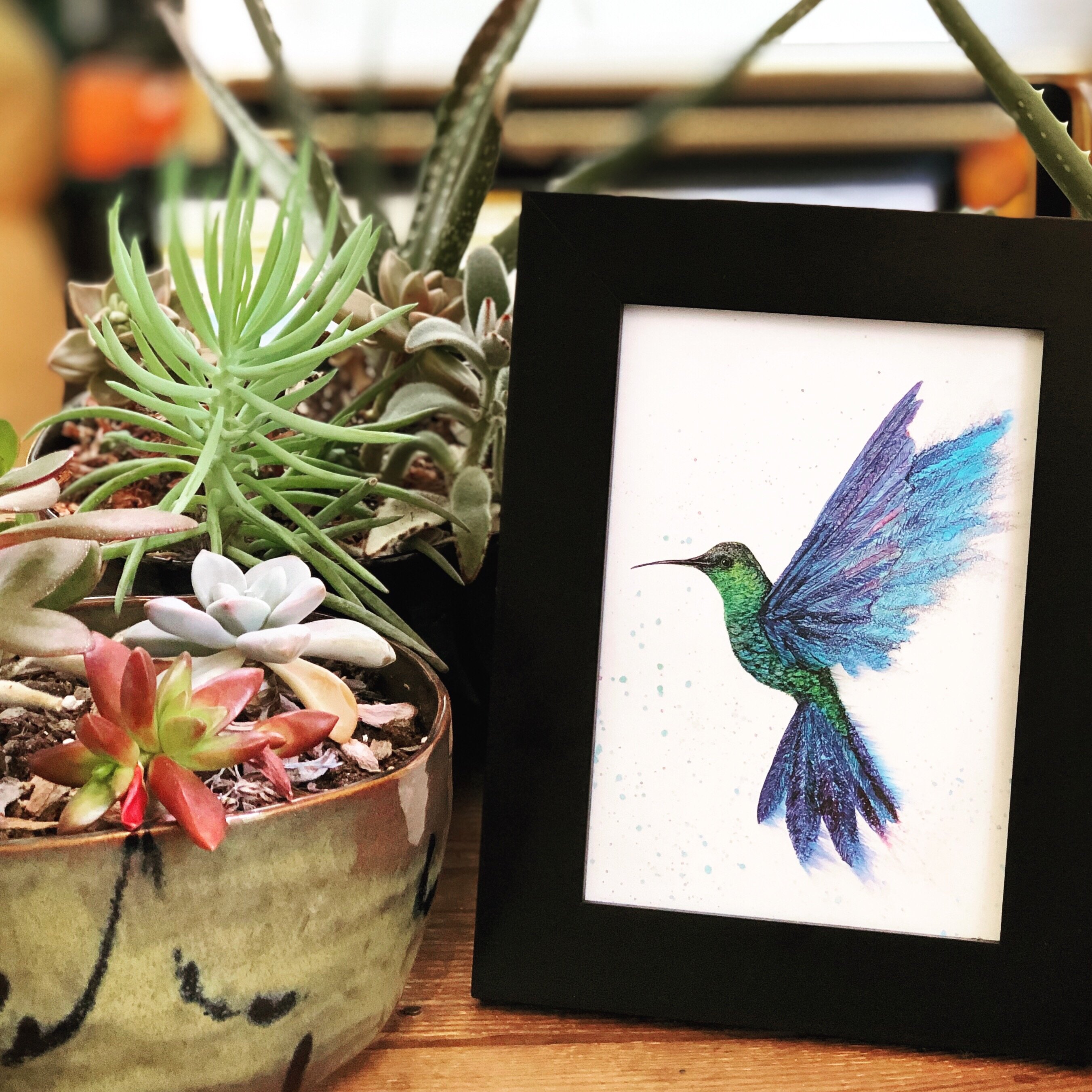 A vibrant art print of a hummingbird in flight, showcasing intricate details and colors created with alcohol inks.