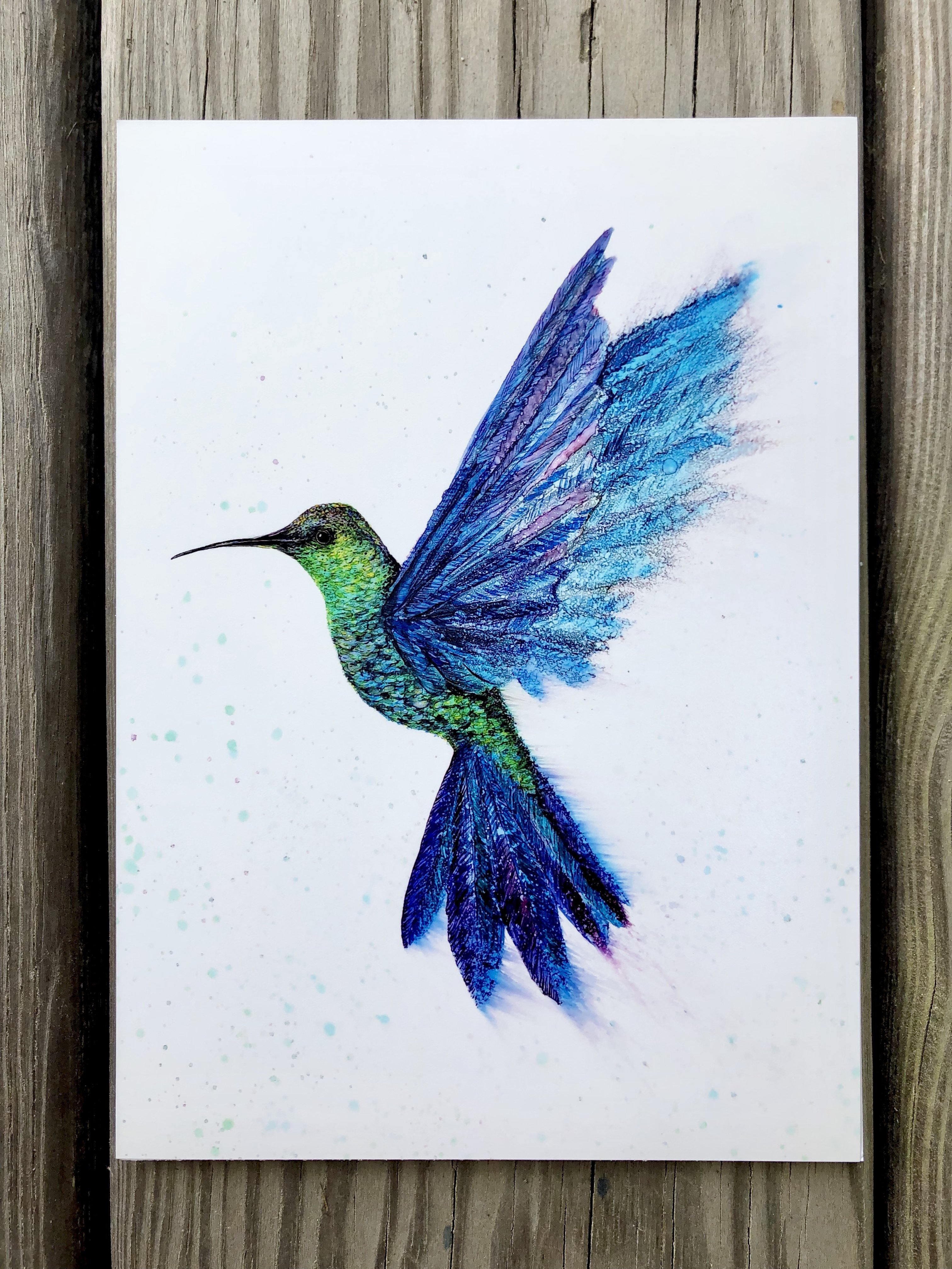 A vibrant art print of a hummingbird in flight, showcasing intricate details and colors created with alcohol inks.