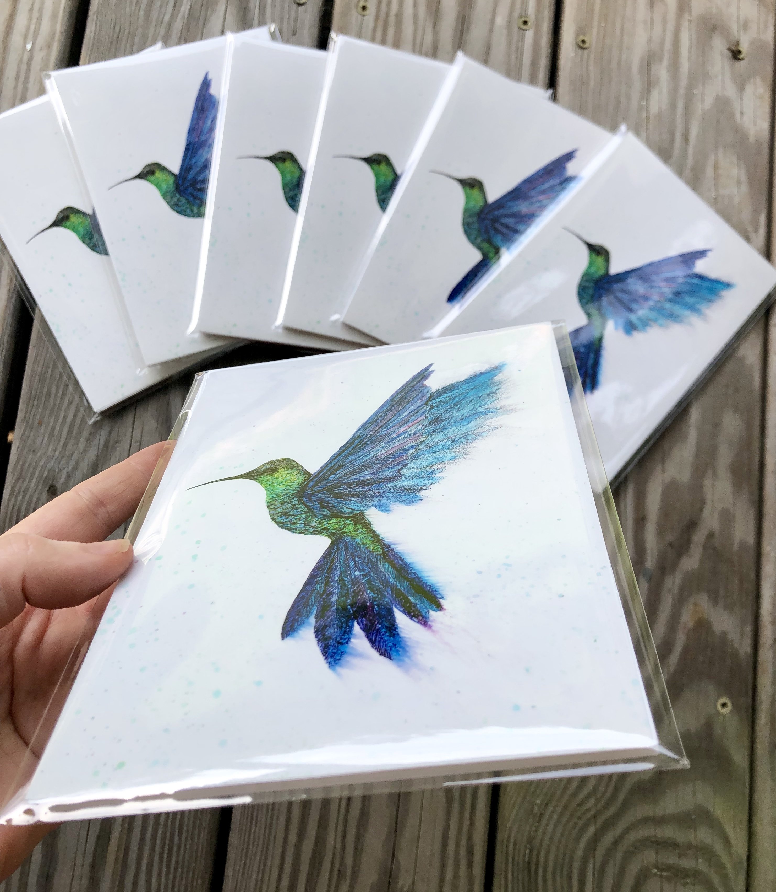 A vibrant art print of a hummingbird in flight, showcasing intricate details and colors created with alcohol inks.
