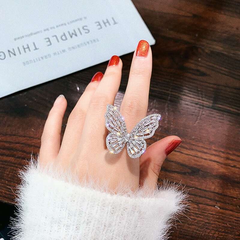 Iced out butterfly ring for women featuring luxury designer bling in white and pink colors, crafted from alloy and zircon with adjustable size.