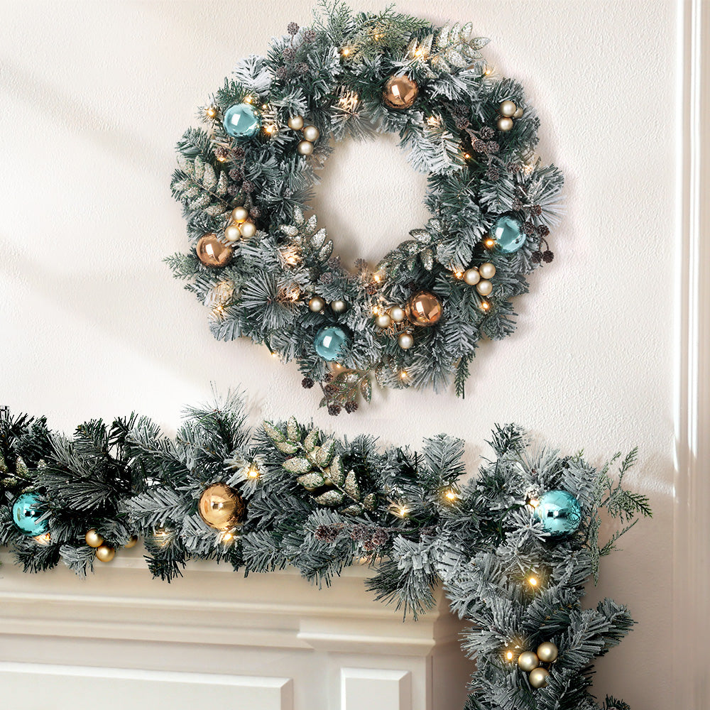 Jingle Jollys Christmas Garland and Wreath set featuring snow-frosted foliage, warm LED lights, and decorative pine cones.