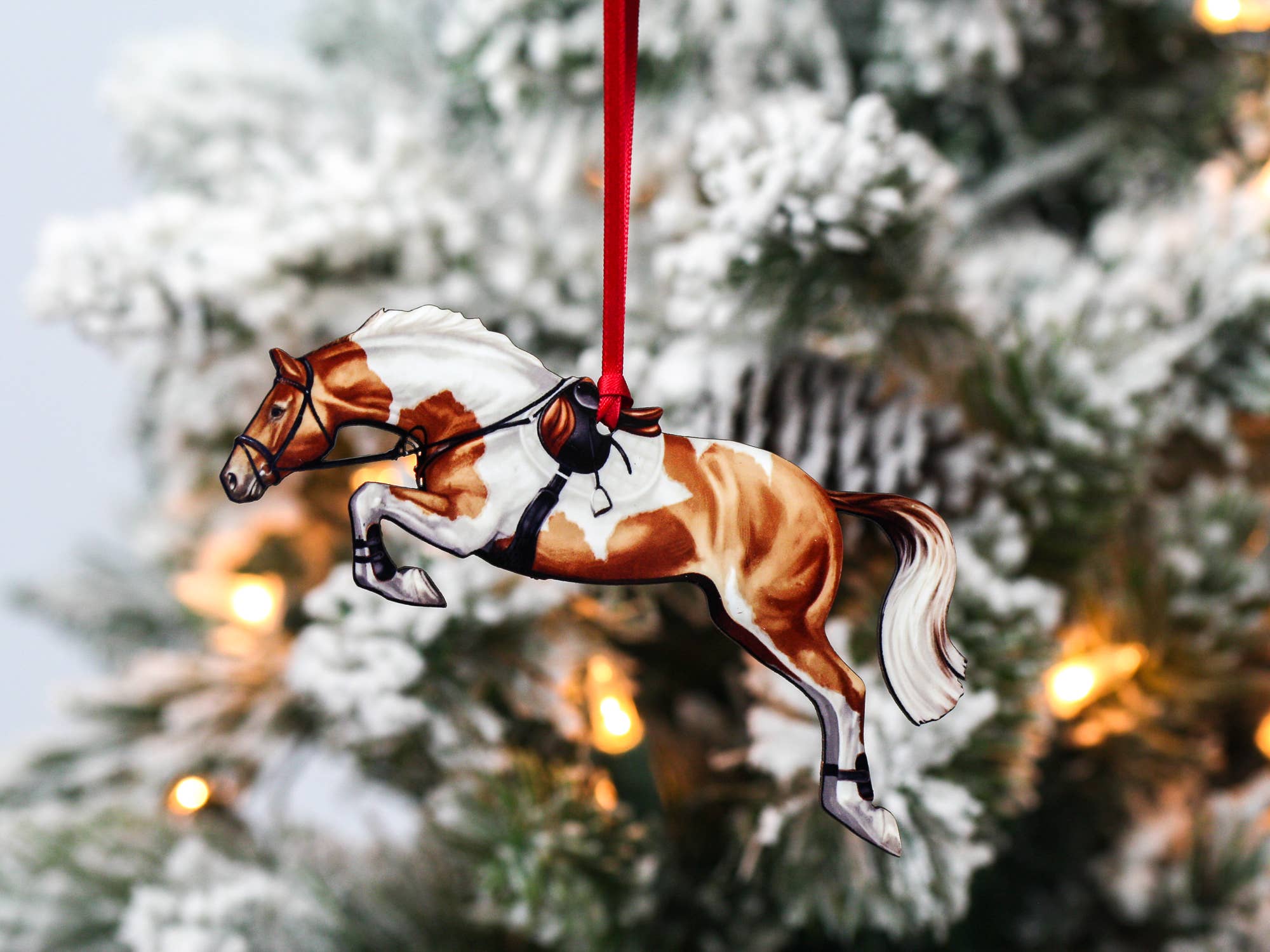 A beautifully crafted chestnut and white tobiano jumping horse ornament made from composite wood, featuring a glossy finish and a ribbon for hanging.