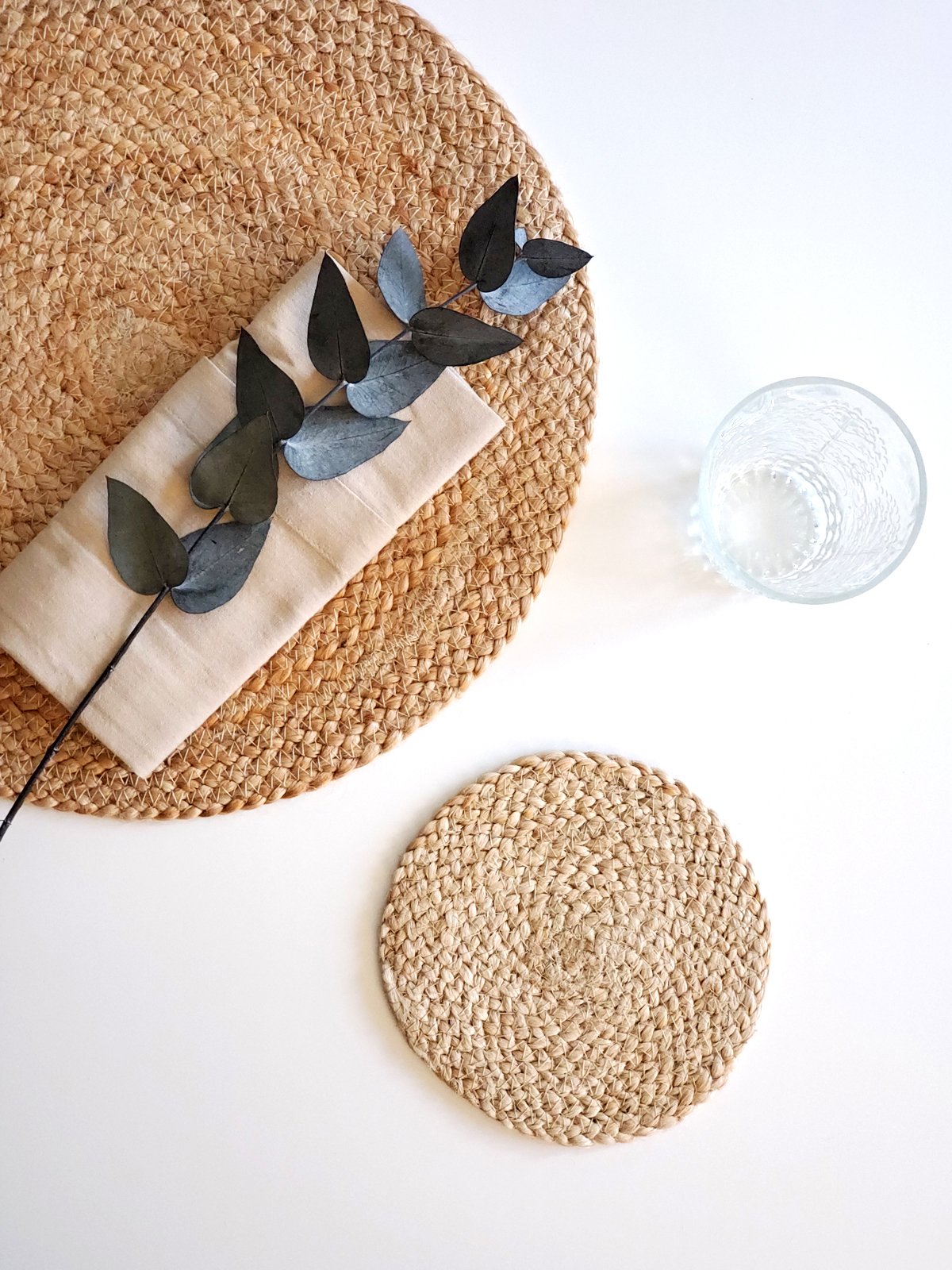 Set of four handmade jute coasters, round and natural in color, designed to protect surfaces from scratches and moisture.