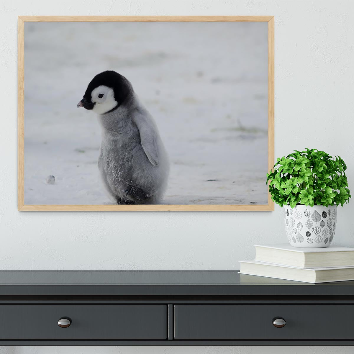 A beautifully framed print of a lone penguin chick, showcasing its adorable features and vibrant colors, set in a handmade frame.