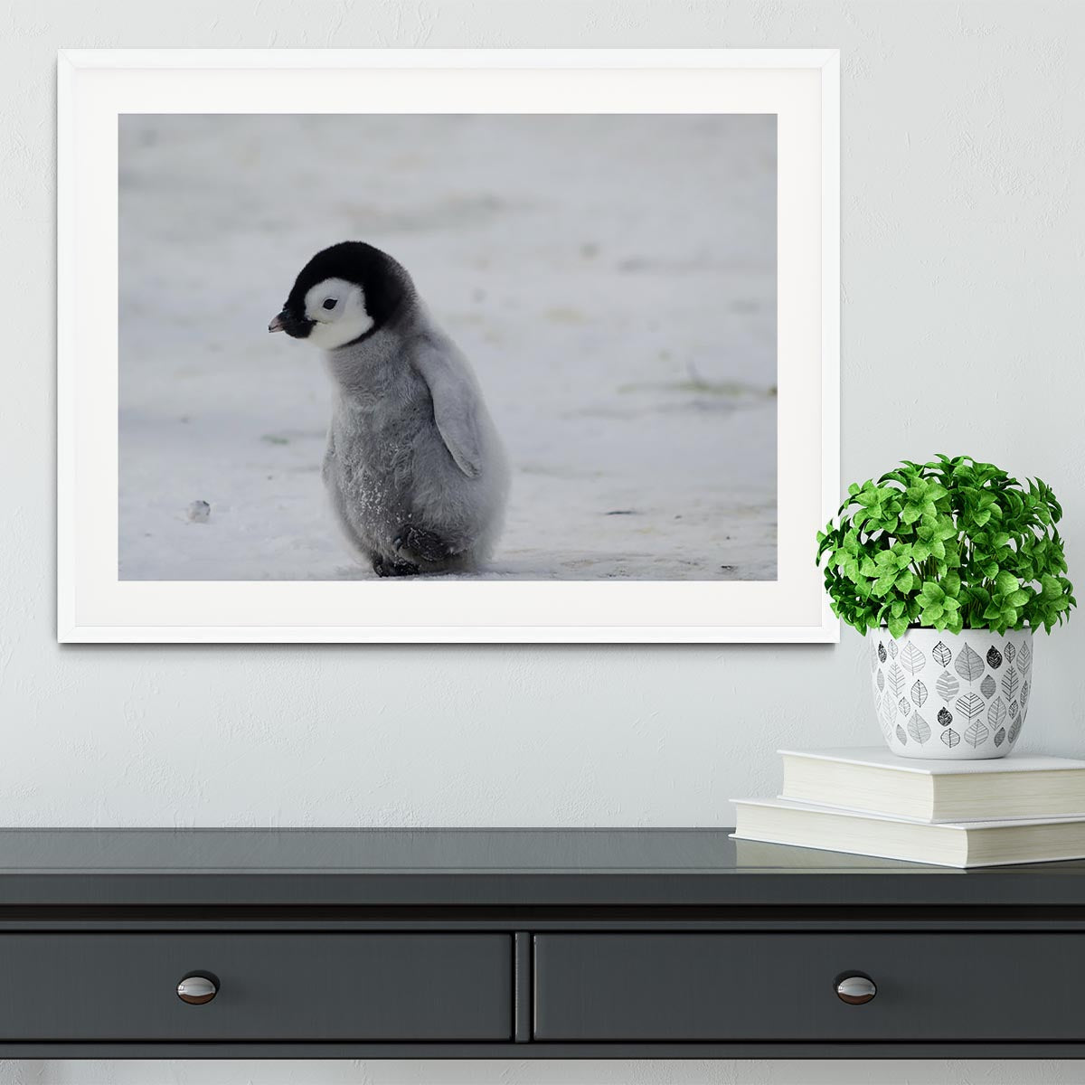 A beautifully framed print of a lone penguin chick, showcasing its adorable features and vibrant colors, set in a handmade frame.