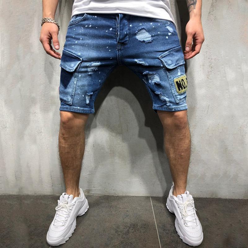 Men's ripped embroidered denim shorts in light wash, featuring knee-length cut and stylish character pattern.