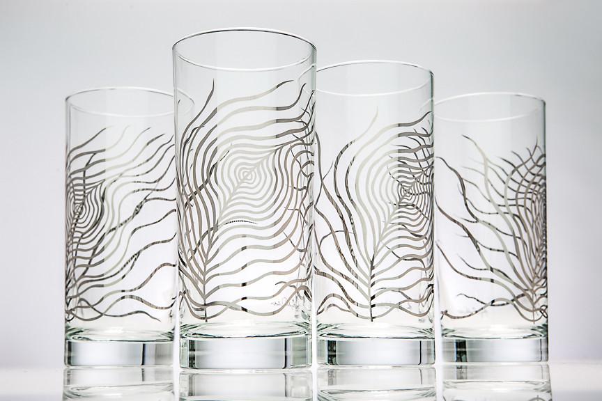 A pair of elegant metallic silver glasses featuring a peacock feather design, reflecting light beautifully.