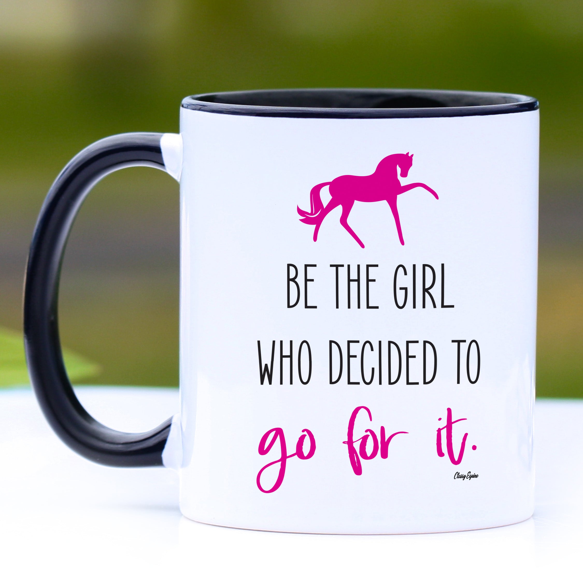 A stylish 11 oz ceramic mug with a black handle and black interior, featuring the inspirational phrase 'Be the girl who decided to go for it'.