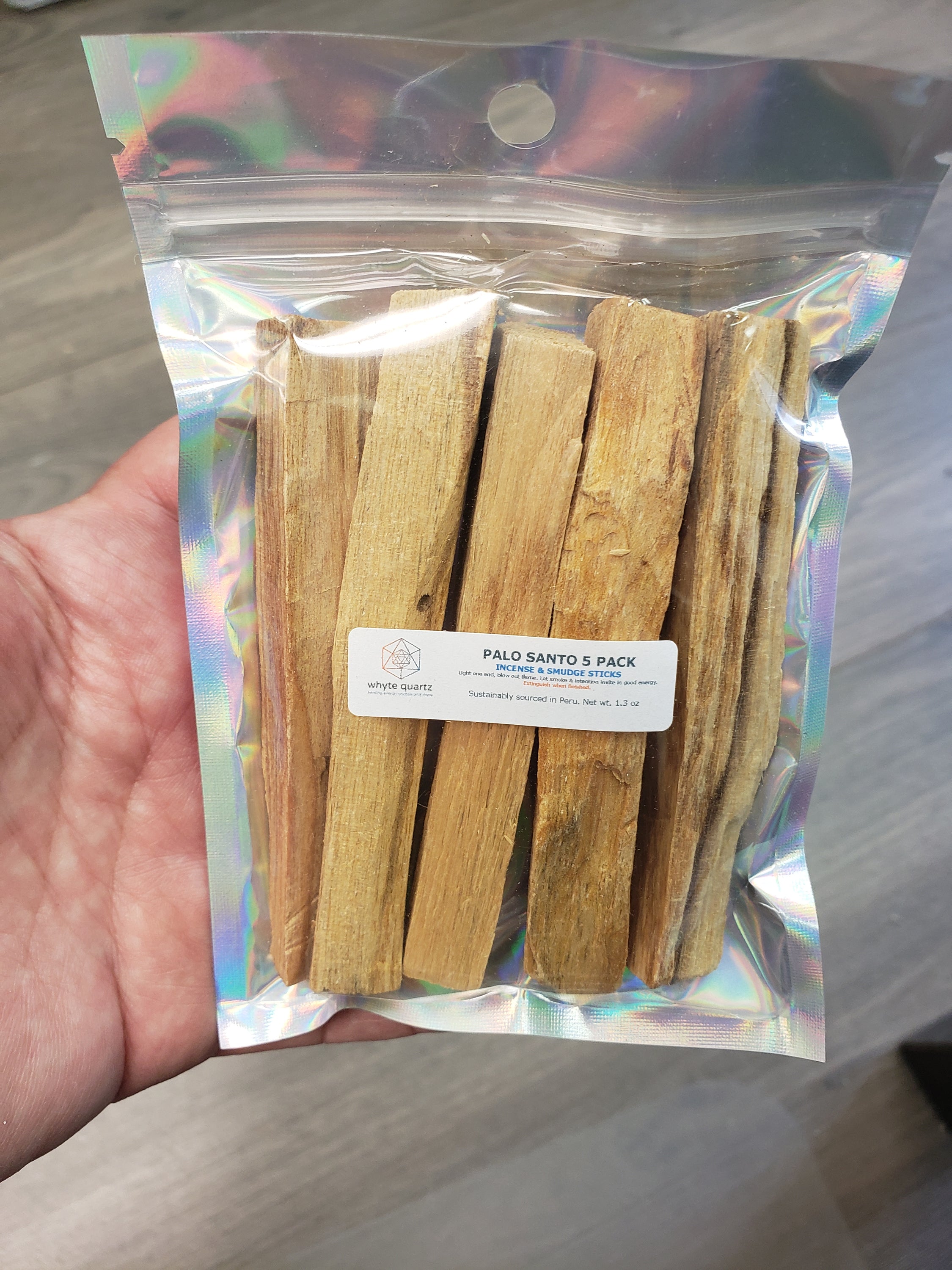 A pack of 5 sustainably sourced Palo Santo sticks, each approximately 4 inches long, displayed on a wooden surface.