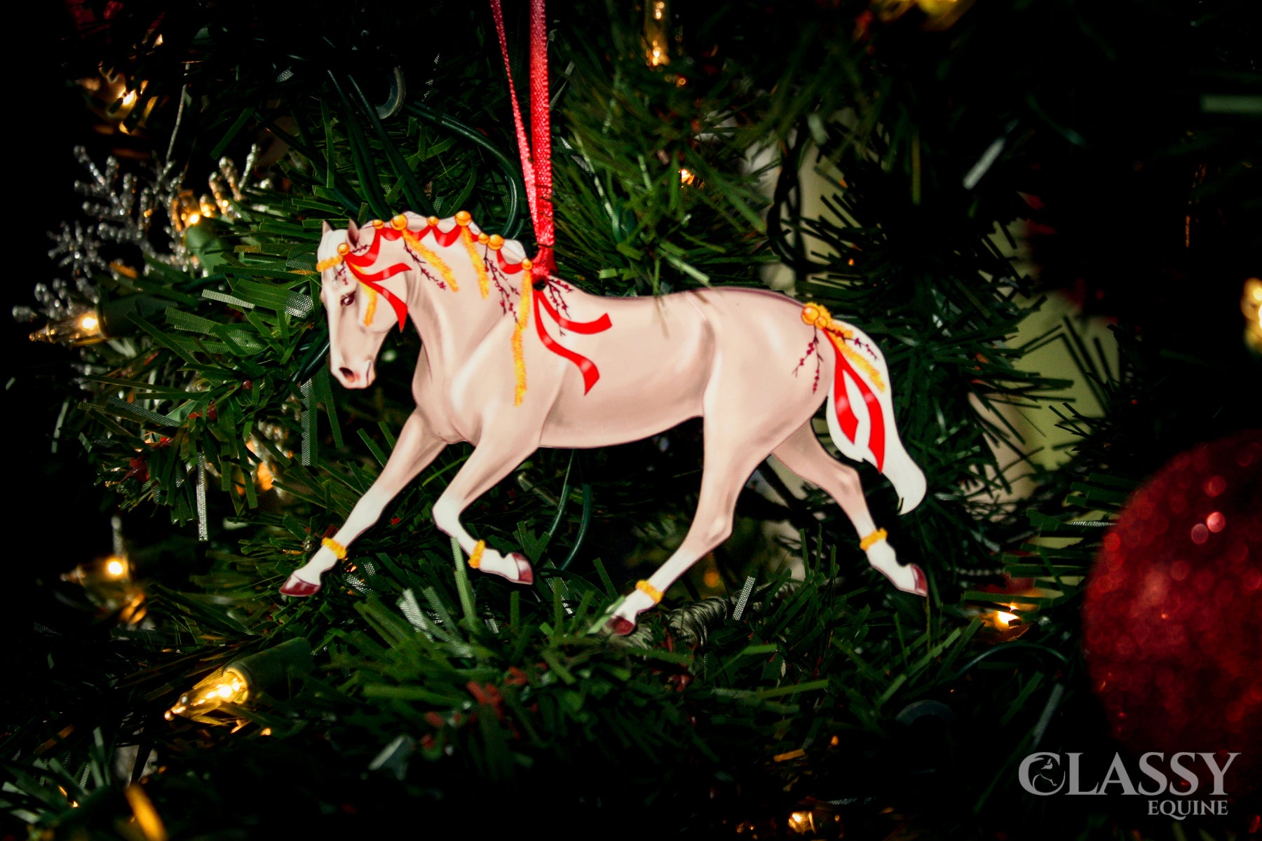 A beautifully crafted Palomino horse ornament with red ribbons and yellow garland, perfect for Christmas decoration.