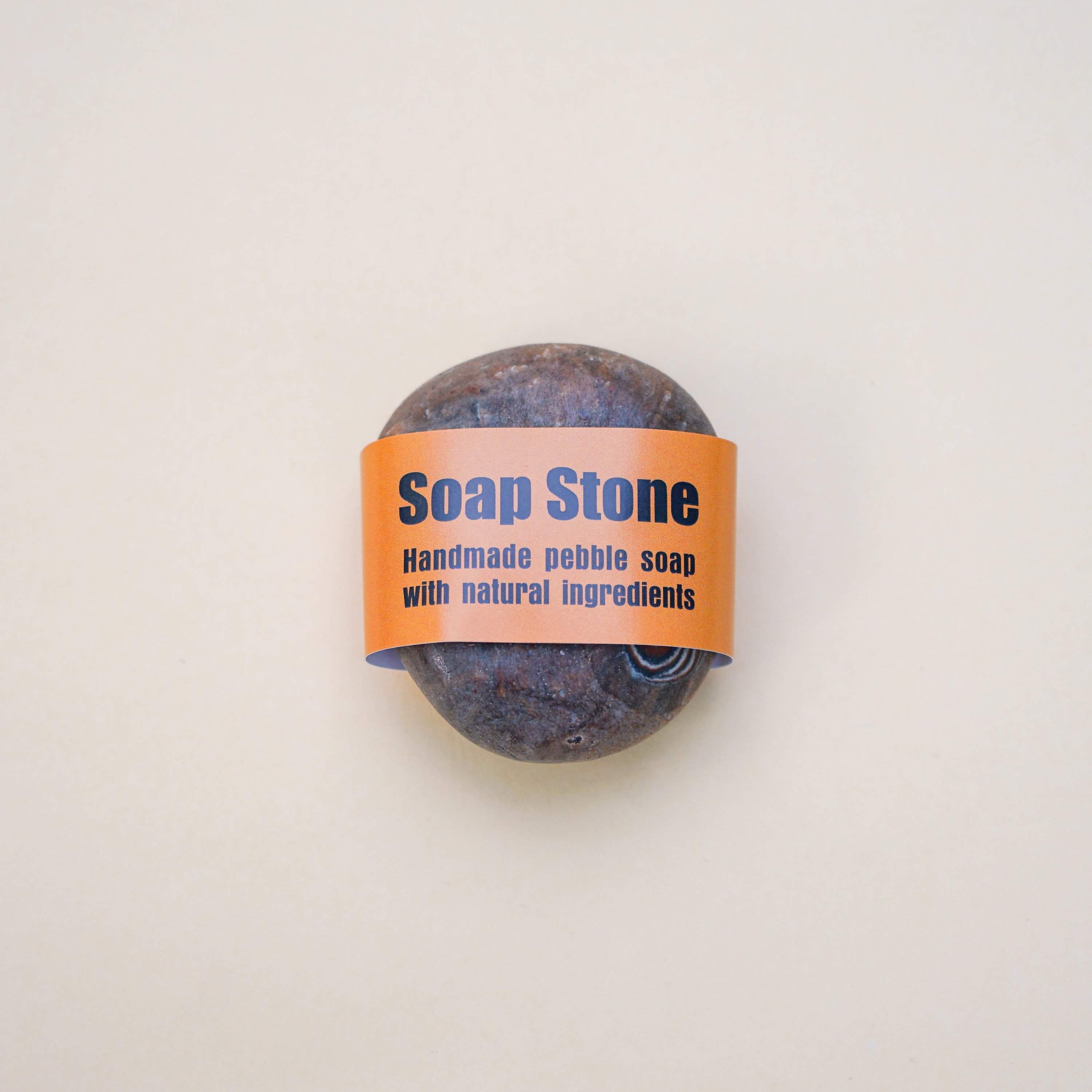 Handmade brown pebble soap with a unique spiral pattern, showcasing its natural ingredients and artistic design.