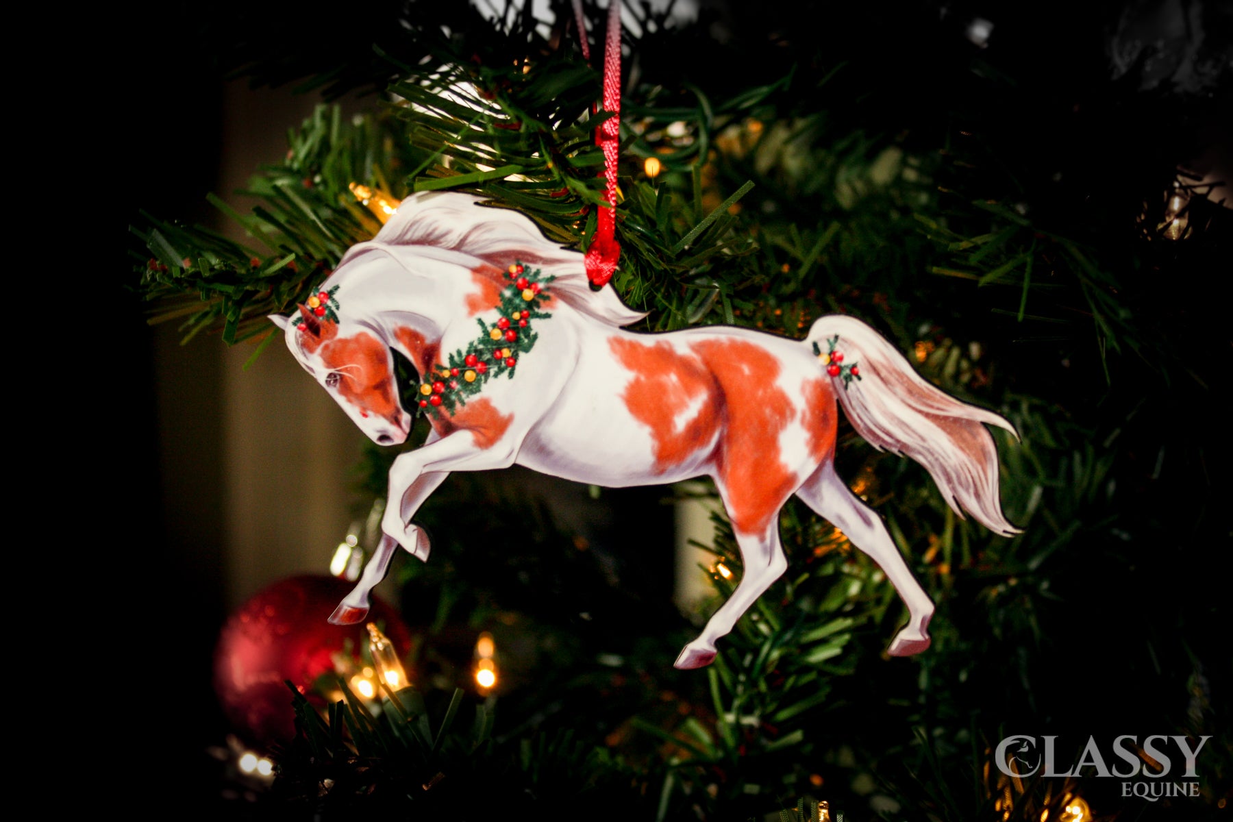 A beautifully crafted Pinto Horse Christmas Ornament featuring a chestnut and white tobiano horse adorned with a festive wreath and holiday decorations.