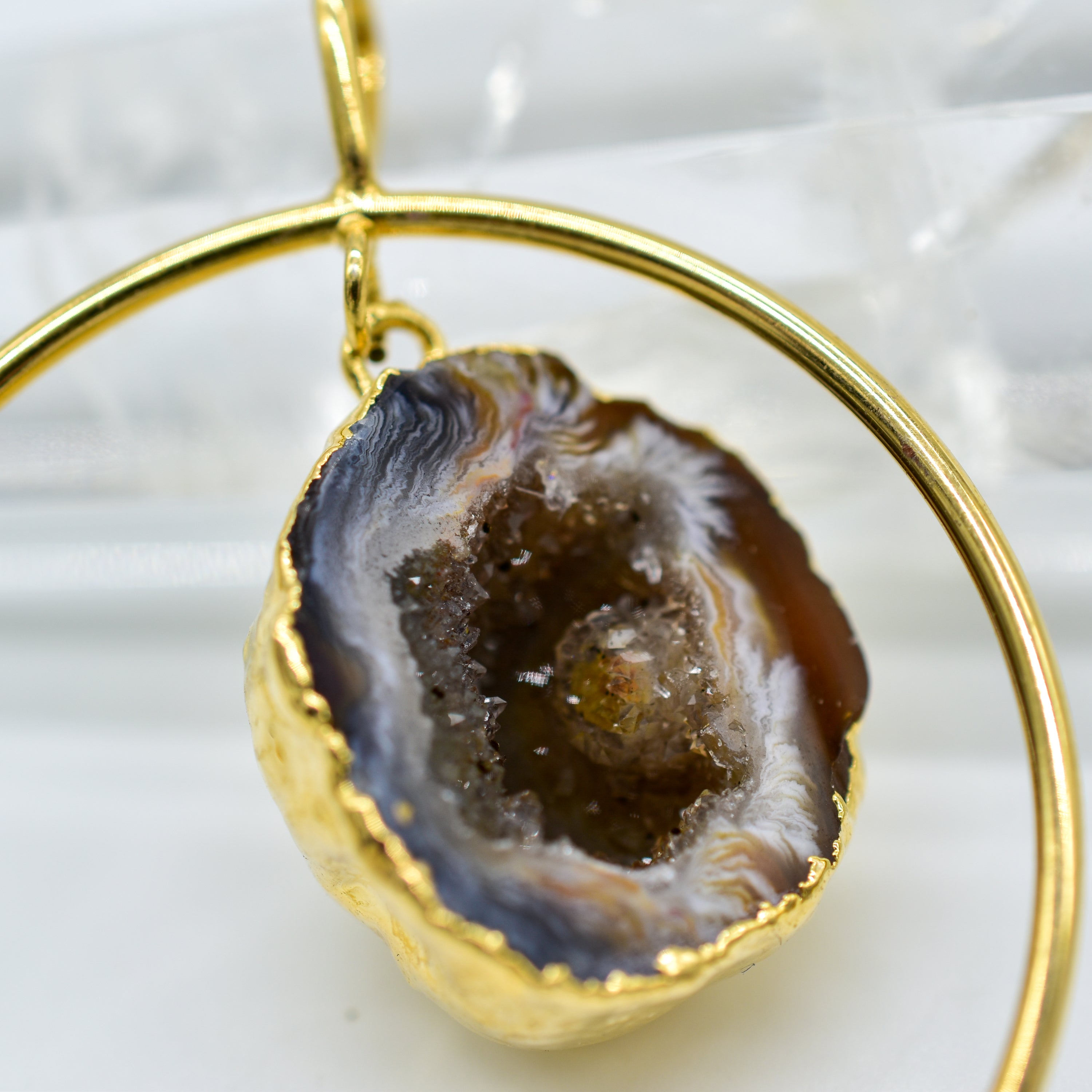 A stunning Plated Agate Geode pendant featuring a druzy interior, set in a silver or gold hoop, showcasing its unique design and craftsmanship.