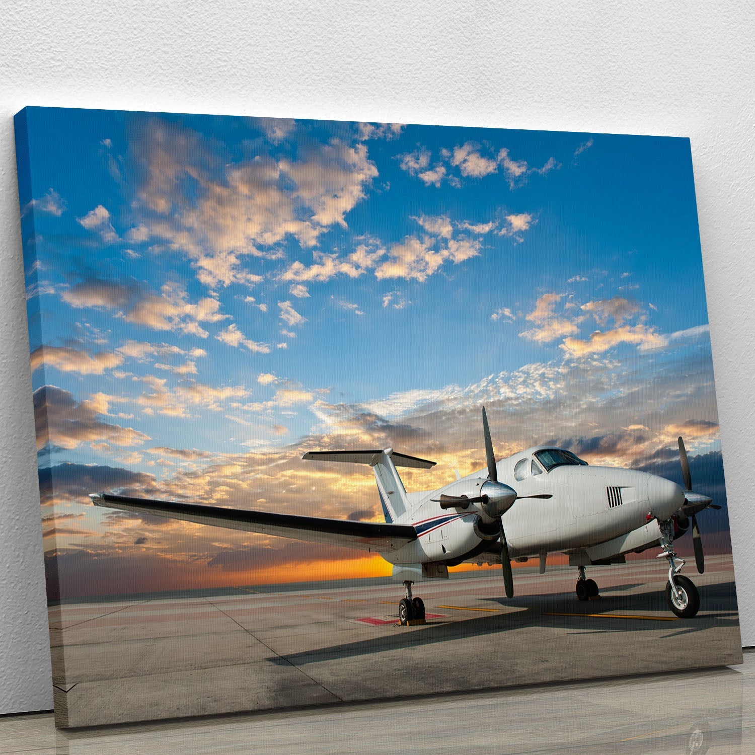 A vibrant canvas print of a propeller plane parked at an airport, showcasing detailed aircraft features and a clear blue sky.