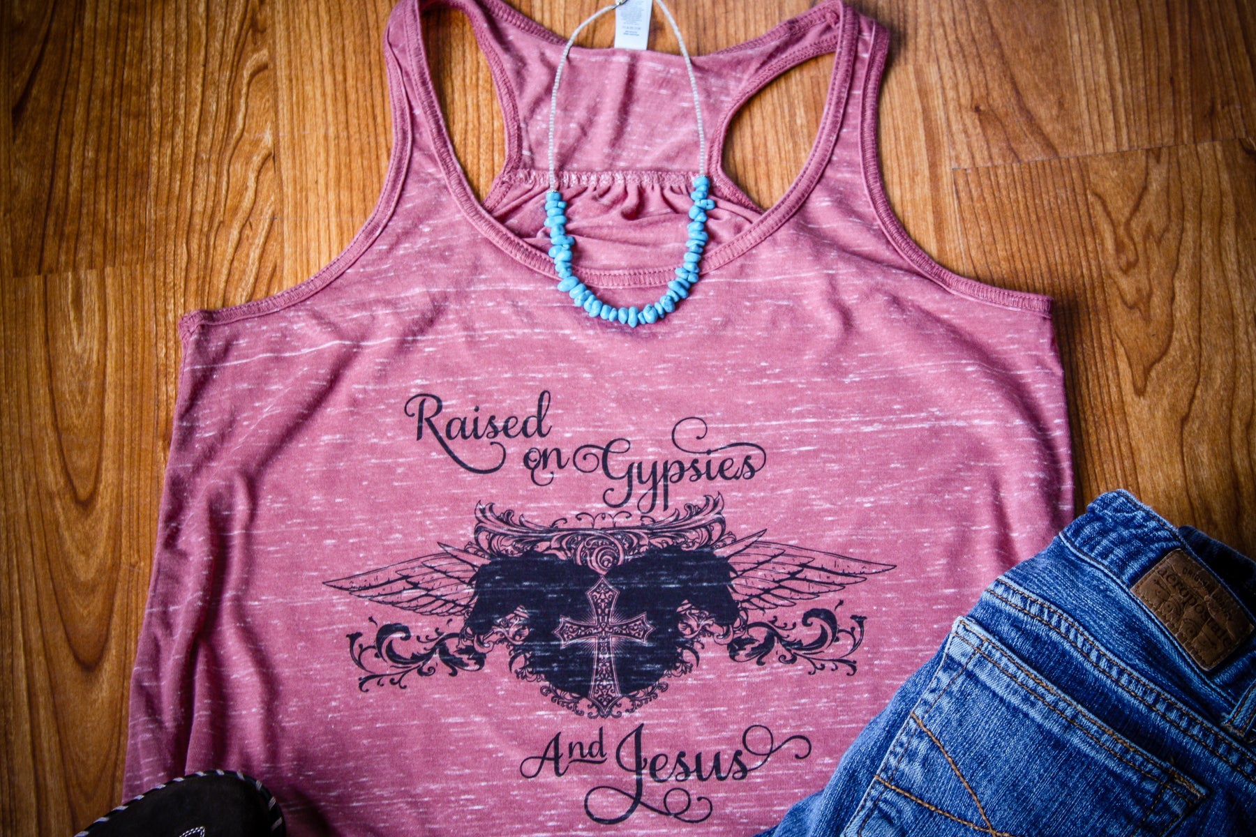 Flowy tank top featuring the design 'Raised on Gypsies and Jesus' in black graphics, available in various colors and sizes.