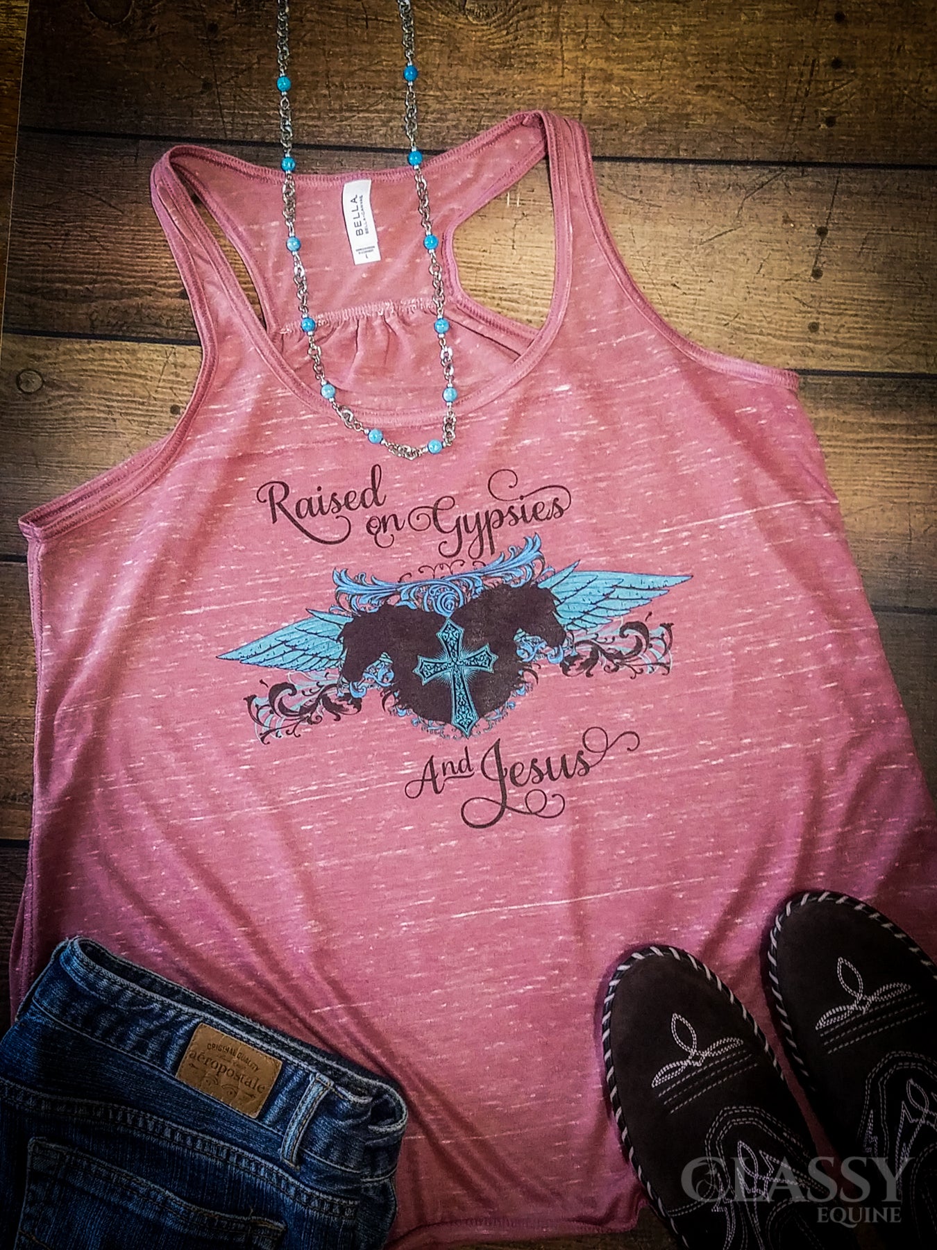 A vibrant Neon Pink flowy tank top featuring the phrase 'Raised on Gypsies and Jesus', showcasing its relaxed fit and soft fabric.