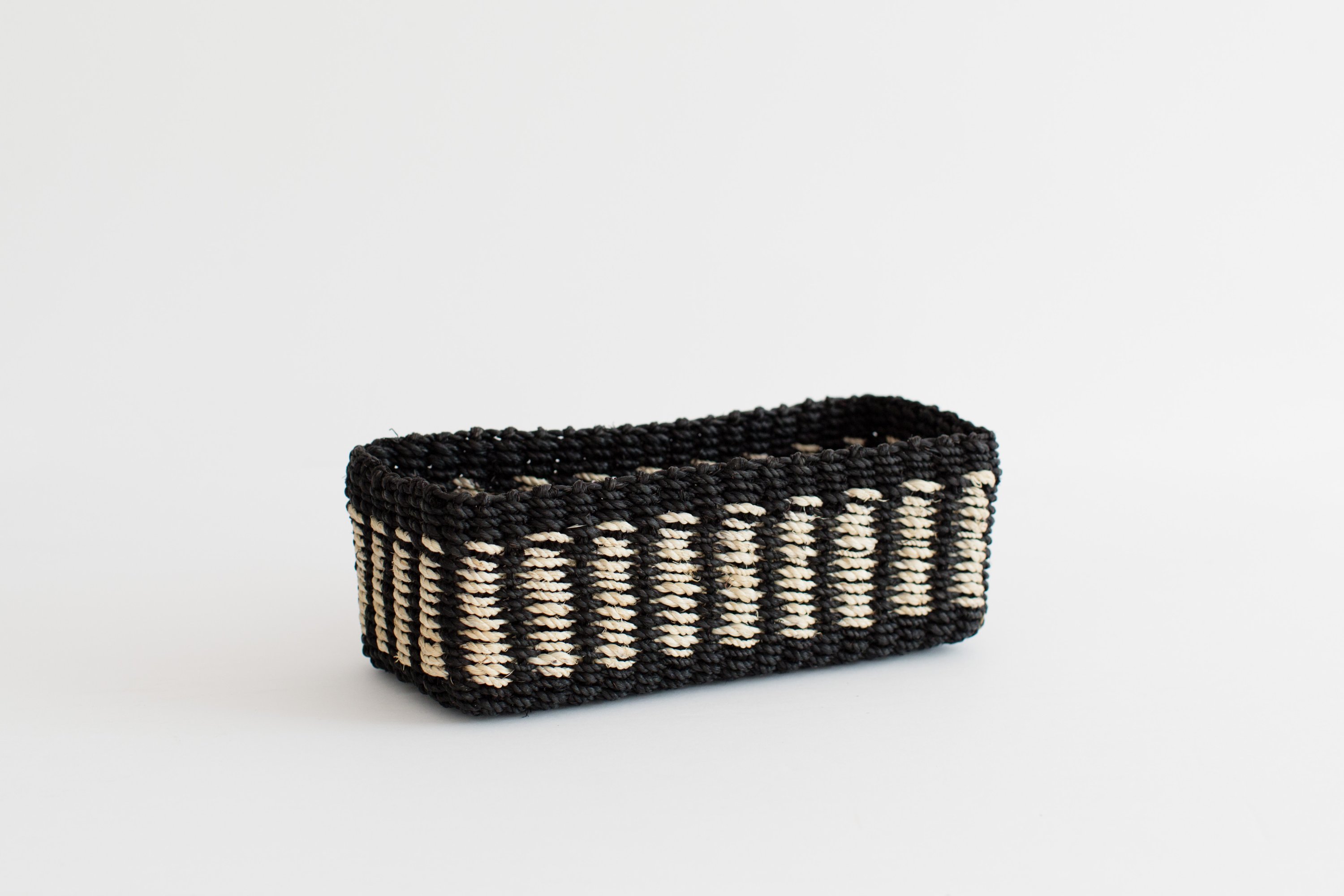 Handwoven seagrass storage tray with black and white band, perfect for organizing small items.
