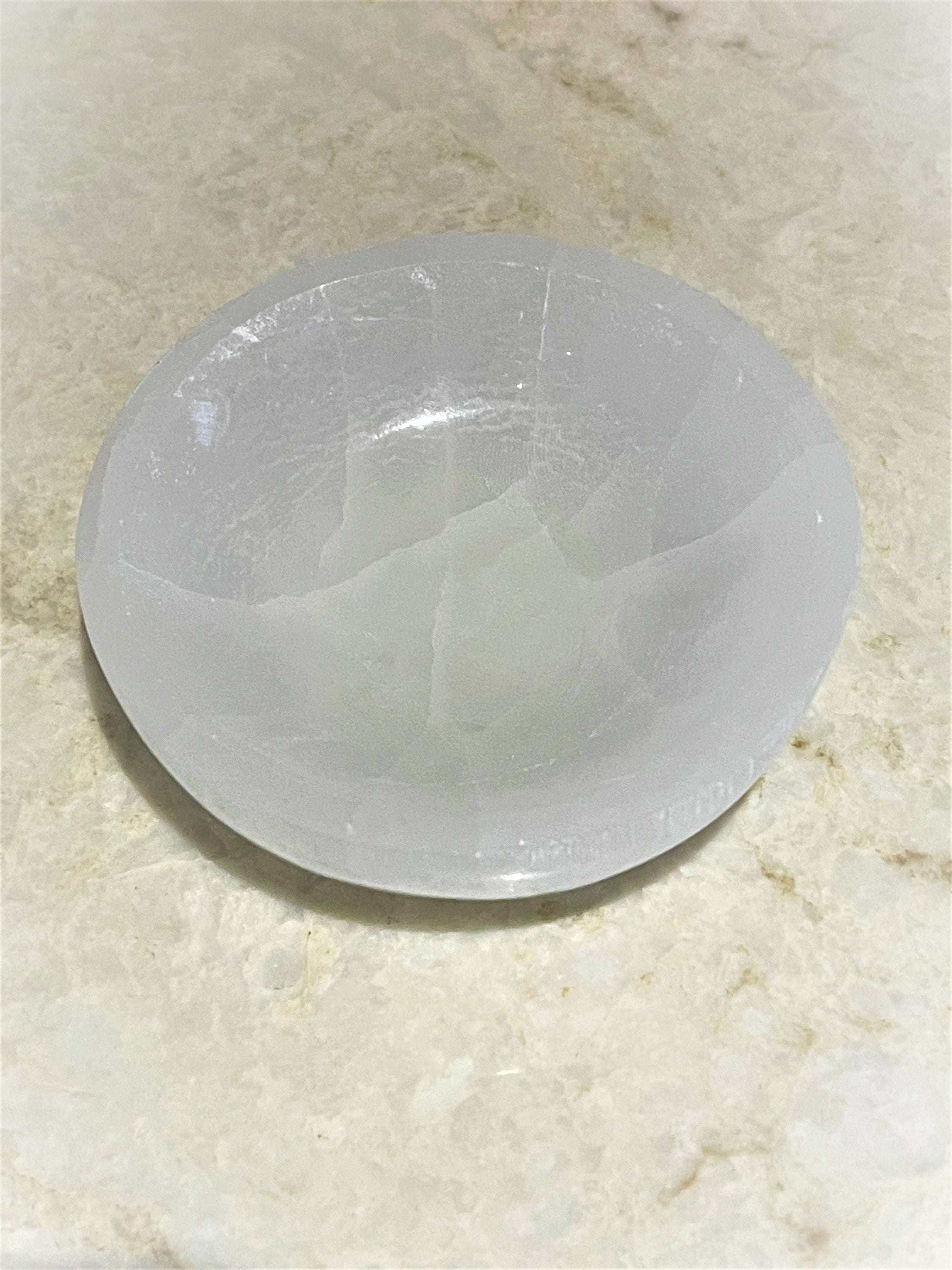 A hand-carved Selenite Healing Bowl, 3.5-4 inches in diameter, showcasing its unique natural patterns and soft glow.