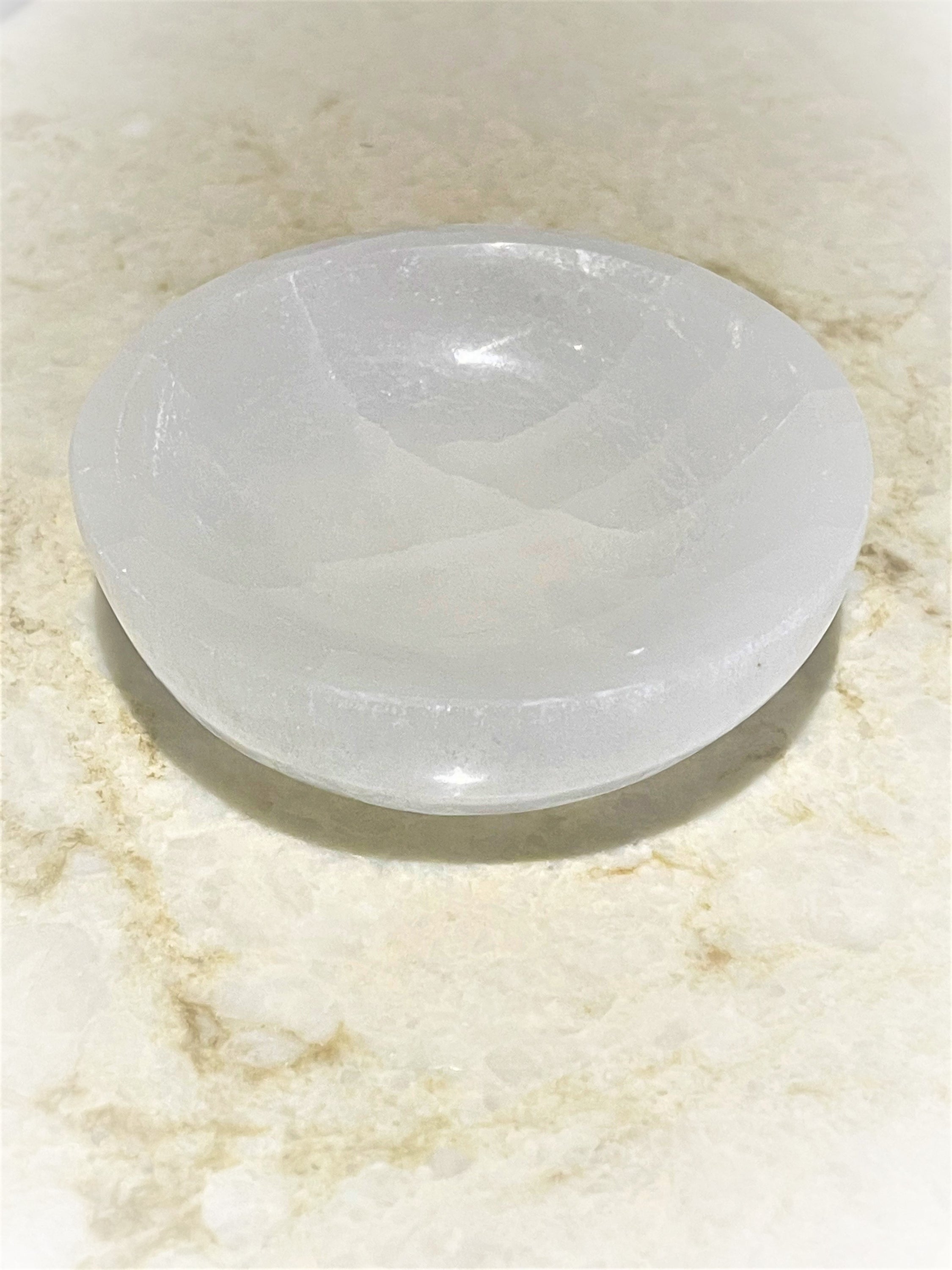 A hand-carved Selenite Healing Bowl, 3.5-4 inches in diameter, showcasing its unique natural patterns and soft glow.