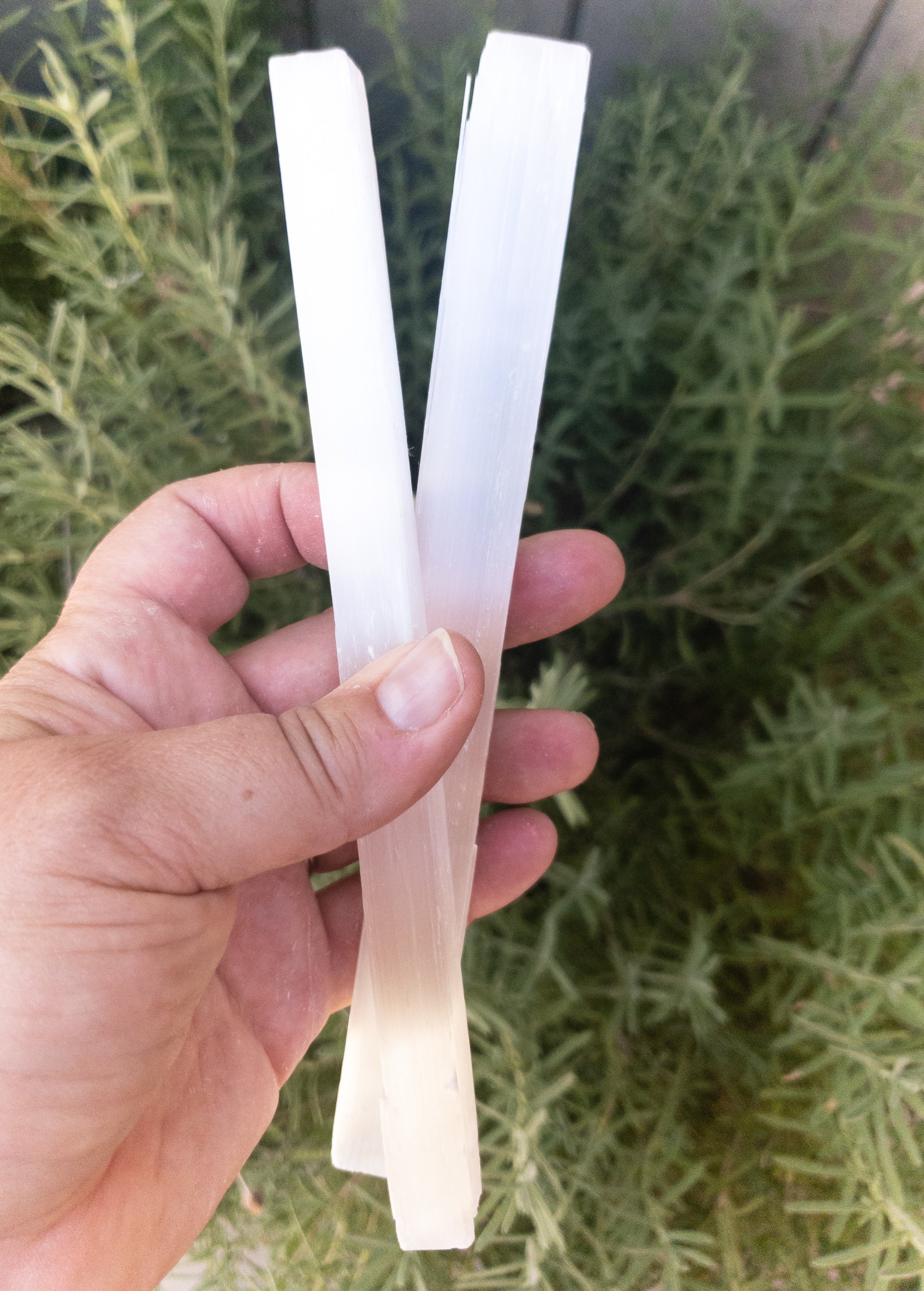 An 8-inch long selenite stick, showcasing its natural imperfections and smooth surface, ideal for cleansing crystals.