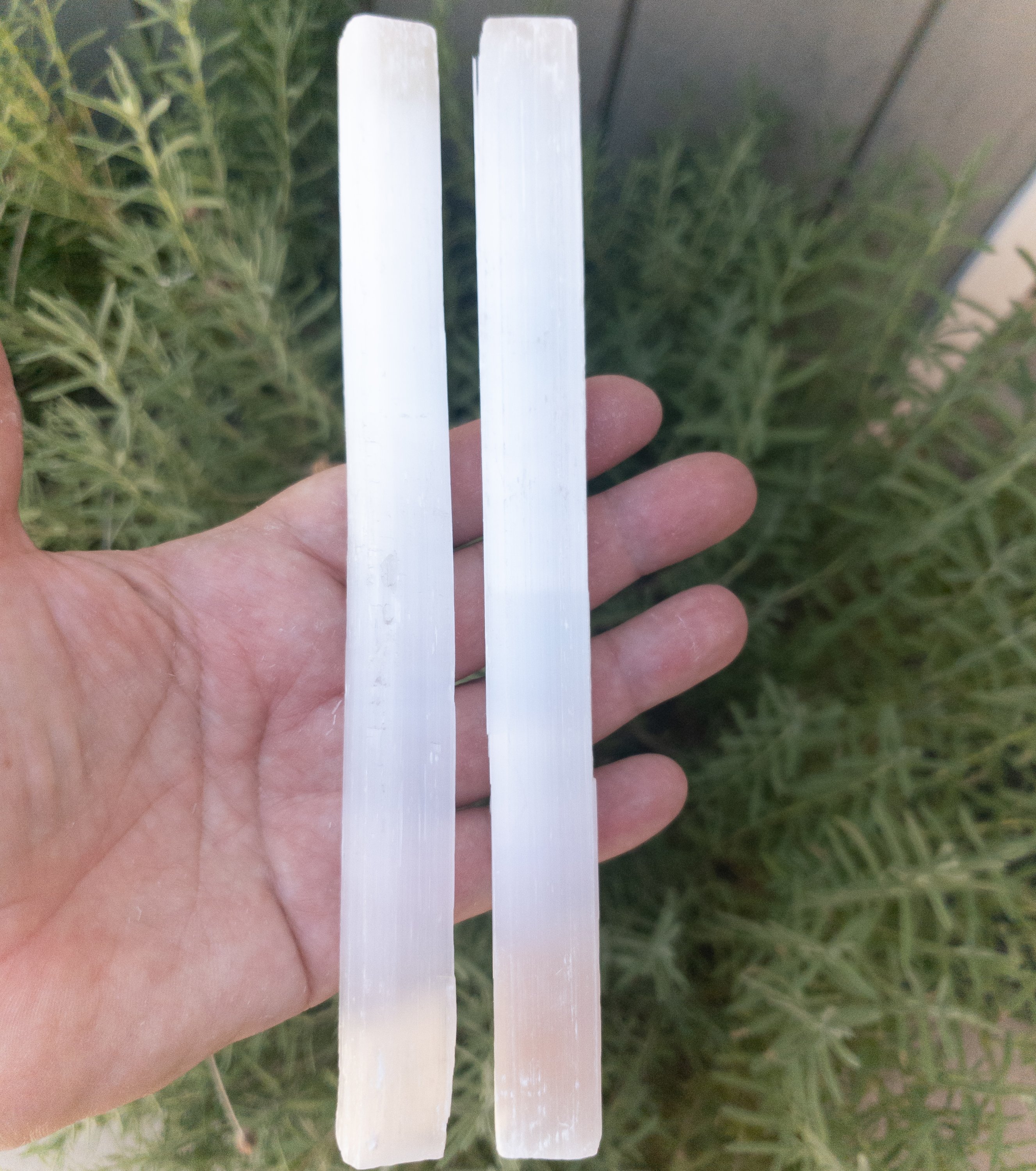 An 8-inch long selenite stick, showcasing its natural imperfections and smooth surface, ideal for cleansing crystals.